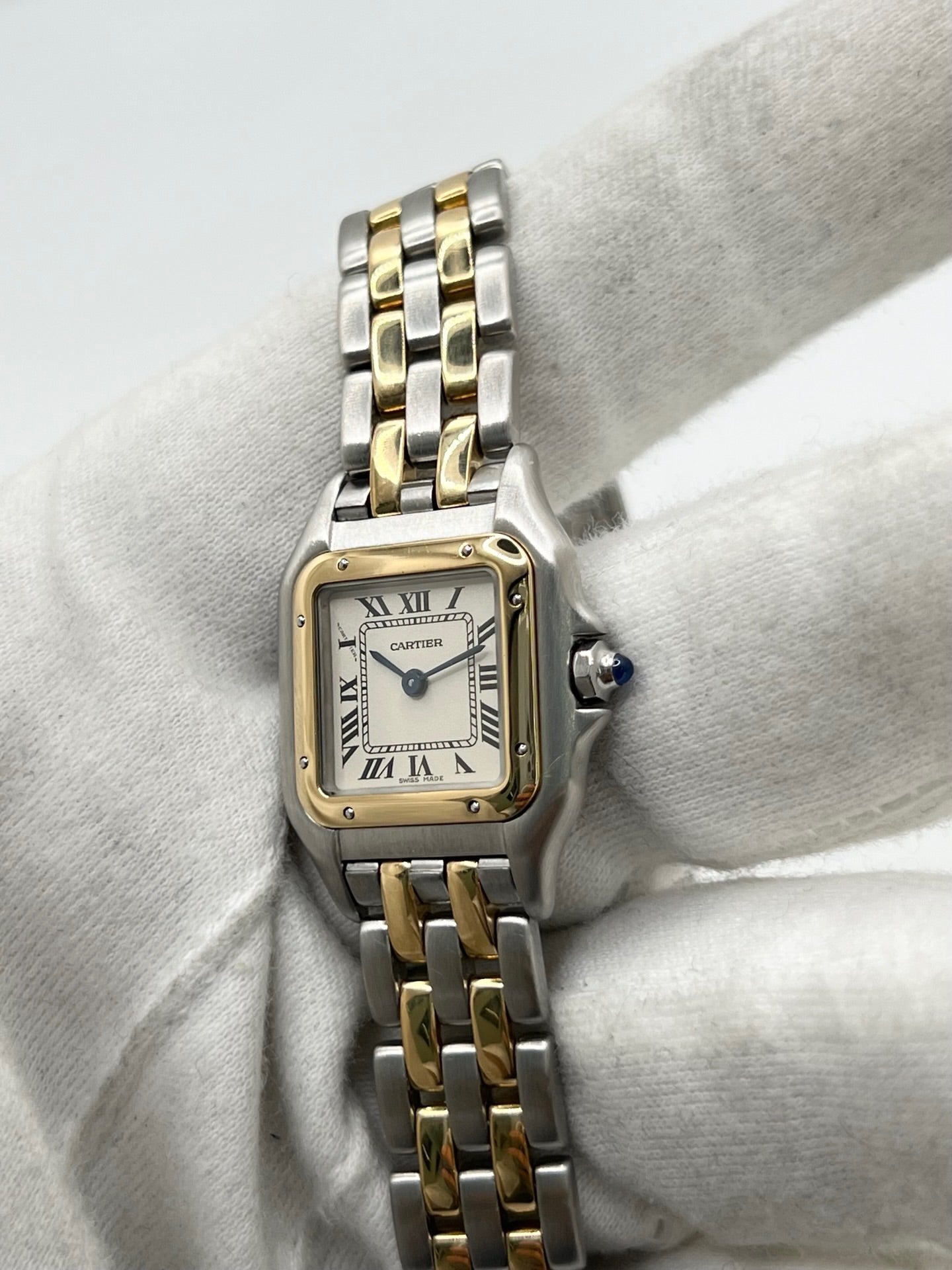 Montre Cartier Panthère référence 66921 pour femme en or jaune et acier, fabriquée en 1985 et équipée d'un mouvement quartz Swiss movement. Son boîtier rectangulaire de 22 x 30 mm est sublimé par une lunette en or jaune, un cadran blanc à chiffres romains et un verre saphir. Cette montre Cartier Panthère bicolore dispose d'un bracelet en or et acier avec boucle déployante. Vendue avec son coffret et ses papiers d'origine, elle est en très bon état et révisée en interne.