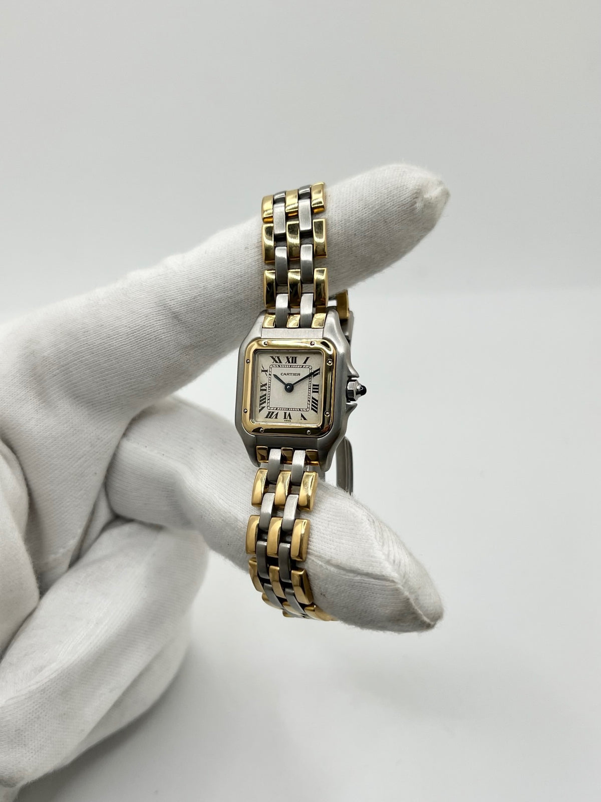 Montre Cartier Panthère 1057917 pour femme, modèle emblématique de la maison Cartier datant de 1989. Cette montre de luxe vintage associe élégamment l’or et l’acier, avec un cadran blanc raffiné, un verre saphir et un mouvement à quartz. La Cartier Panthère référence 1057917 est proposée d’occasion en très bon état, avec son coffret et ses papiers d’origine. Révisée en interne le 19 octobre 2026, cette montre Cartier Panthère en or et acier allie élégance intemporelle et savoir-faire horloger.