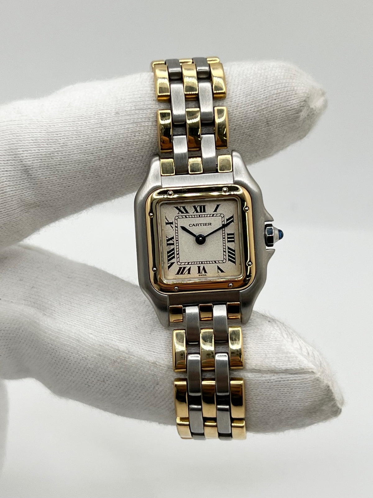 Montre Cartier Panthère 1057917 pour femme, modèle emblématique de la maison Cartier datant de 1989. Cette montre de luxe vintage associe élégamment l’or et l’acier, avec un cadran blanc raffiné, un verre saphir et un mouvement à quartz. La Cartier Panthère référence 1057917 est proposée d’occasion en très bon état, avec son coffret et ses papiers d’origine. Révisée en interne le 19 octobre 2026, cette montre Cartier Panthère en or et acier allie élégance intemporelle et savoir-faire horloger.