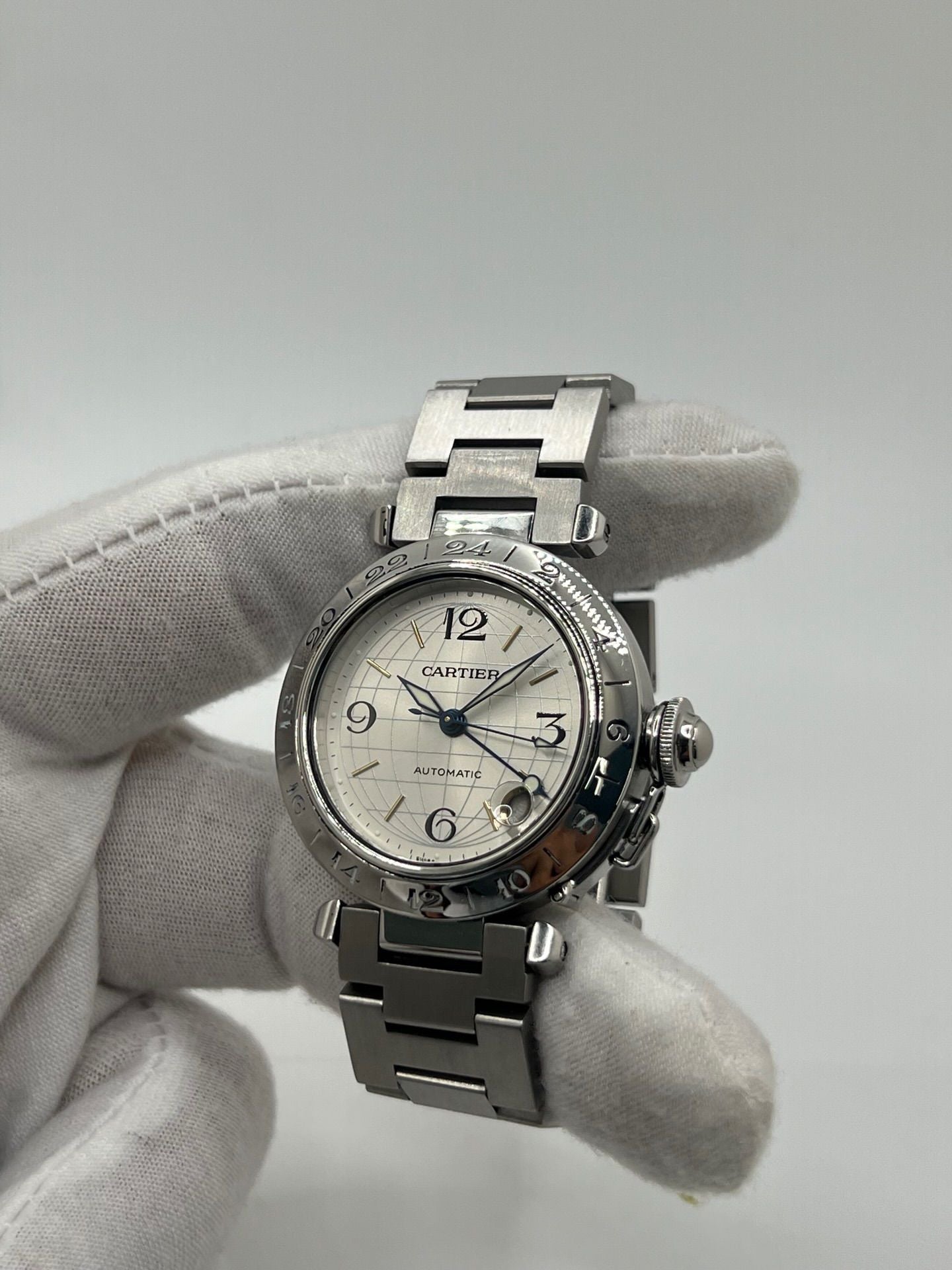 Montre Cartier Pasha C GMT réf. 2377 en acier, dotée d’un mouvement automatique calibre 048. Son boîtier de 35 mm abrite un cadran argenté à chiffres arabes, protégé par un verre saphir. Étanche jusqu’à 10 ATM, cette montre élégante et fonctionnelle est équipée d’un bracelet en acier et d’une boucle déployante double plis.