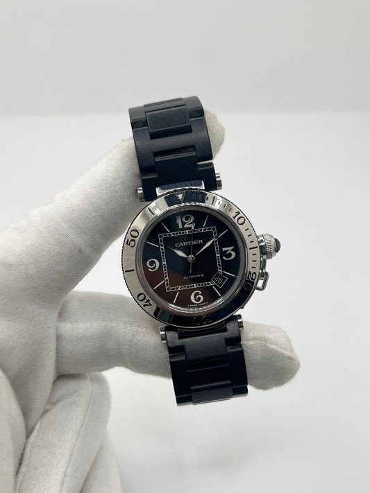 Montre Cartier Pasha Seatimer référence 2790 en acier inoxydable avec boîtier de 40 mm, mouvement automatique calibre 049 basé sur l'ETA 2892-A2 et réserve de marche de 42 heures. Son cadran noir à chiffres arabes est protégé par un verre saphir. Équipée d'un bracelet en acier avec boucle déployante, cette montre est étanche à 10 ATM et dispose d'un guichet date. Vendue avec son coffret et ses papiers d'origine, révisée en interne et en très bon état.