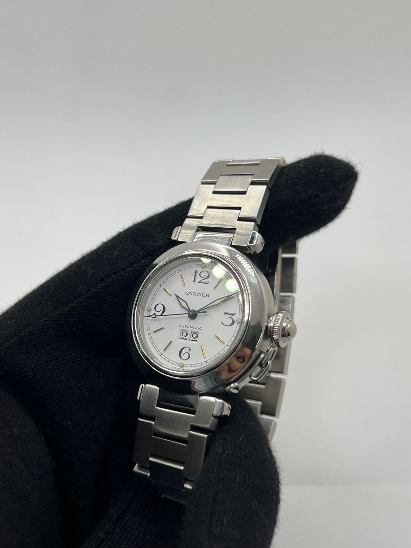 Montre de luxe Cartier Pasha C référence 2475 en acier, équipée d’un mouvement automatique calibre 052. Son boîtier de 35 mm et son cadran blanc à chiffres arabes offrent un style élégant et intemporel. Avec verre saphir, étanchéité 10 ATM et bracelet en acier, cette Pasha C combine performance, précision et raffinement.