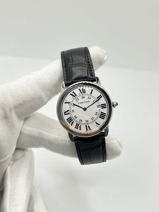 Montre Cartier Ronde Solo en acier avec cadran argent à chiffres romains, mouvement quartz et fonction date. Boîtier rond 36 x 39 mm avec verre saphir et étanchéité 3 ATM. Bracelet en cuir noir avec boucle ardillon en acier. Design classique et élégant, idéal pour homme ou unisexe. Montre d’occasion en très bon état, révisée, avec coffret d’origine.