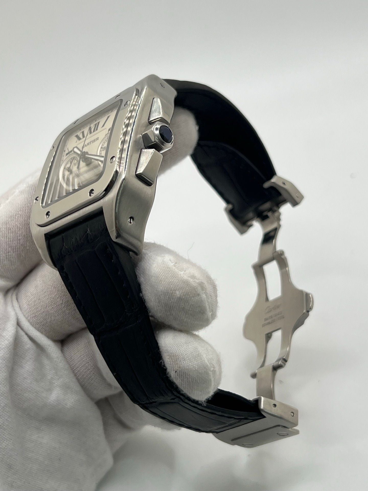 Montre Cartier Santos 100 XL Chronograph pour homme, modèle emblématique au design sport-chic. Boîtier en acier, cadran blanc à chiffres romains, bracelet en cuir noir. Mouvement automatique précis avec chronographe et date. Montre d’occasion en excellent état, révisée, livrée avec coffret d’origine.