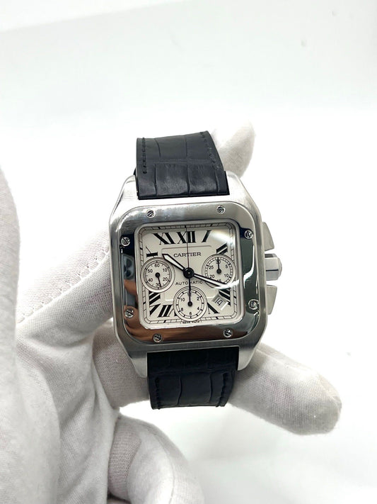 Montre Cartier Santos 100 XL Chronograph pour homme, modèle emblématique au design sport-chic. Boîtier en acier, cadran blanc à chiffres romains, bracelet en cuir noir. Mouvement automatique précis avec chronographe et date. Montre d’occasion en excellent état, révisée, livrée avec coffret d’origine.