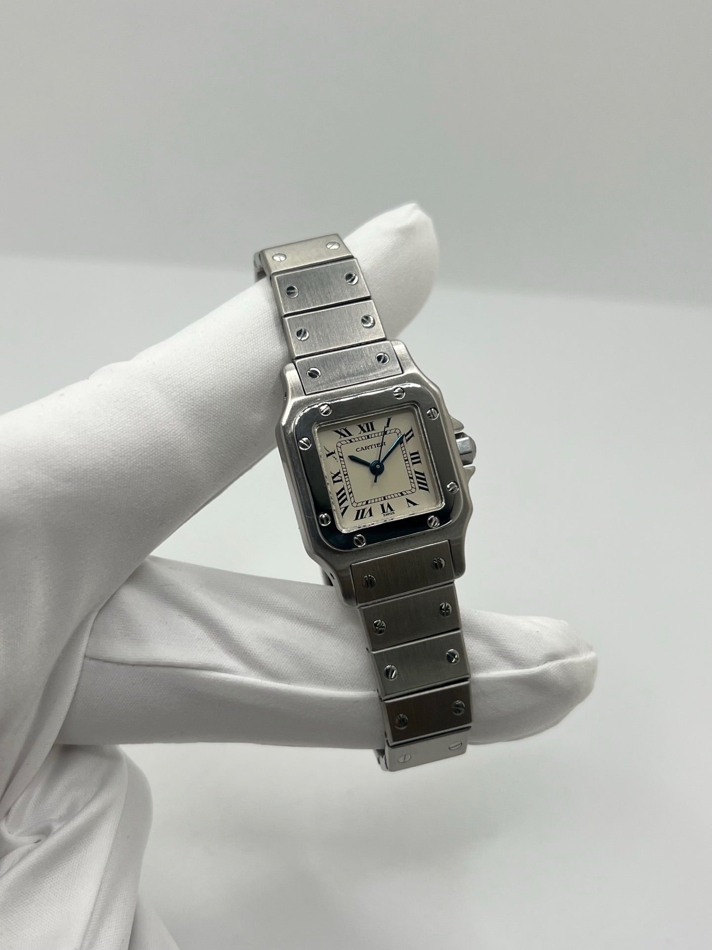 Montre Cartier Santos Lady en acier pour femme, modèle vintage à remontage automatique avec cadran blanc à chiffres romains, boîtier rectangulaire 24 x 35 mm, verre saphir et bracelet acier. Cette montre d’occasion en très bon état présente de légères traces d’usure discrètes. Livrée avec son coffret d’origine, sans papiers, cette Cartier Santos Lady allie élégance intemporelle, raffinement horloger et style iconique pour une collection de montres de luxe femme.
