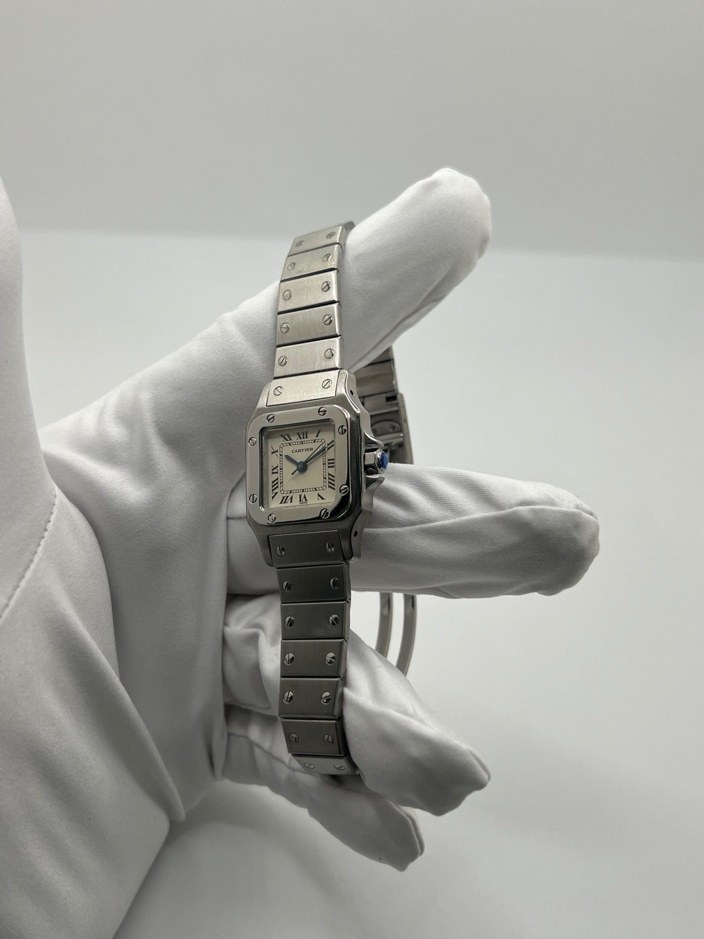 Montre Cartier Santos Lady en acier pour femme, modèle vintage à remontage automatique avec cadran blanc à chiffres romains, boîtier rectangulaire 24 x 35 mm, verre saphir et bracelet acier. Cette montre d’occasion en très bon état présente de légères traces d’usure discrètes. Livrée avec son coffret d’origine, sans papiers, cette Cartier Santos Lady allie élégance intemporelle, raffinement horloger et style iconique pour une collection de montres de luxe femme.