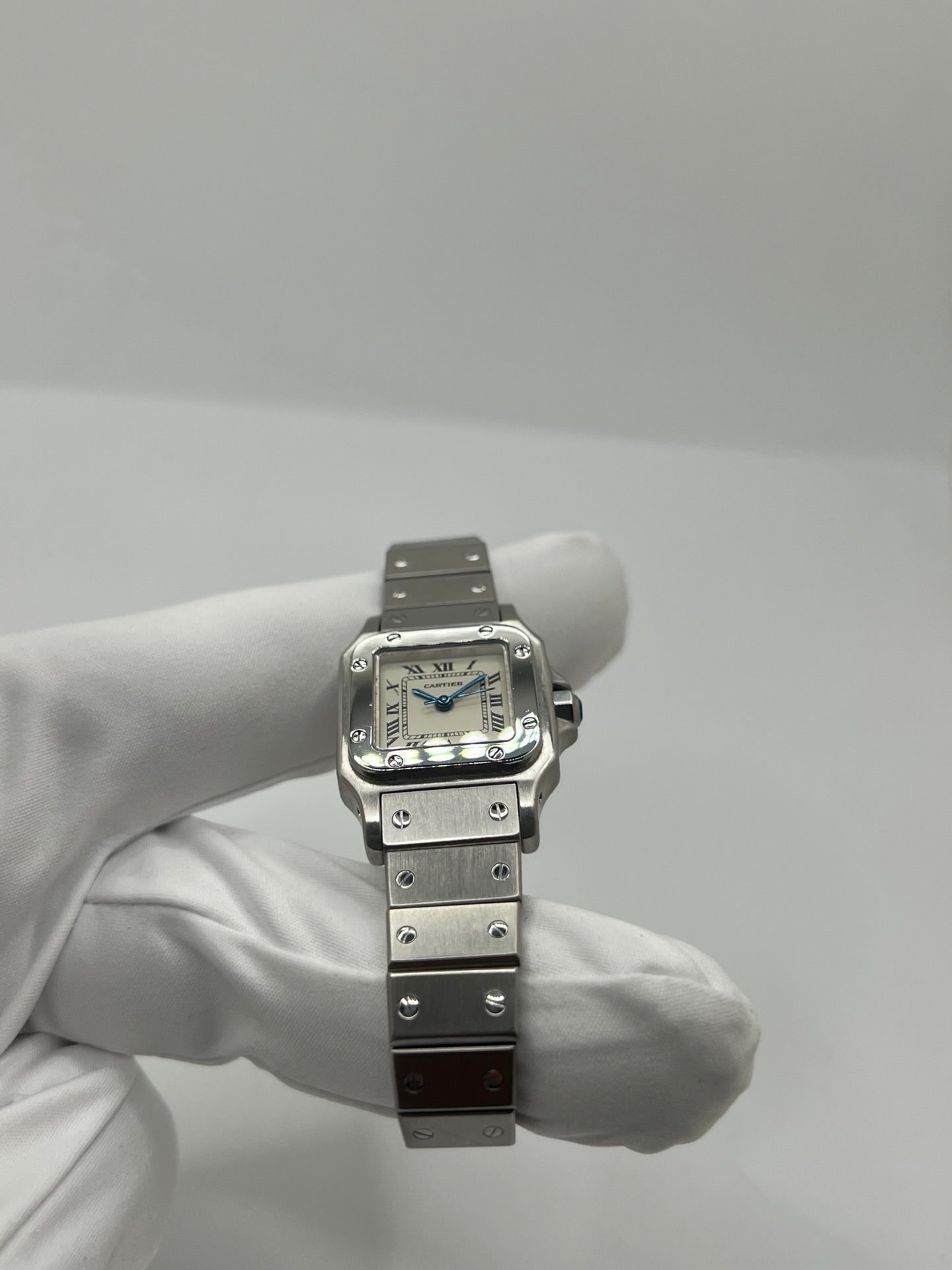 Montre Cartier Santos Lady en acier pour femme, modèle vintage à remontage automatique avec cadran blanc à chiffres romains, boîtier rectangulaire 24 x 35 mm, verre saphir et bracelet acier. Cette montre d’occasion en très bon état présente de légères traces d’usure discrètes. Livrée avec son coffret d’origine, sans papiers, cette Cartier Santos Lady allie élégance intemporelle, raffinement horloger et style iconique pour une collection de montres de luxe femme.