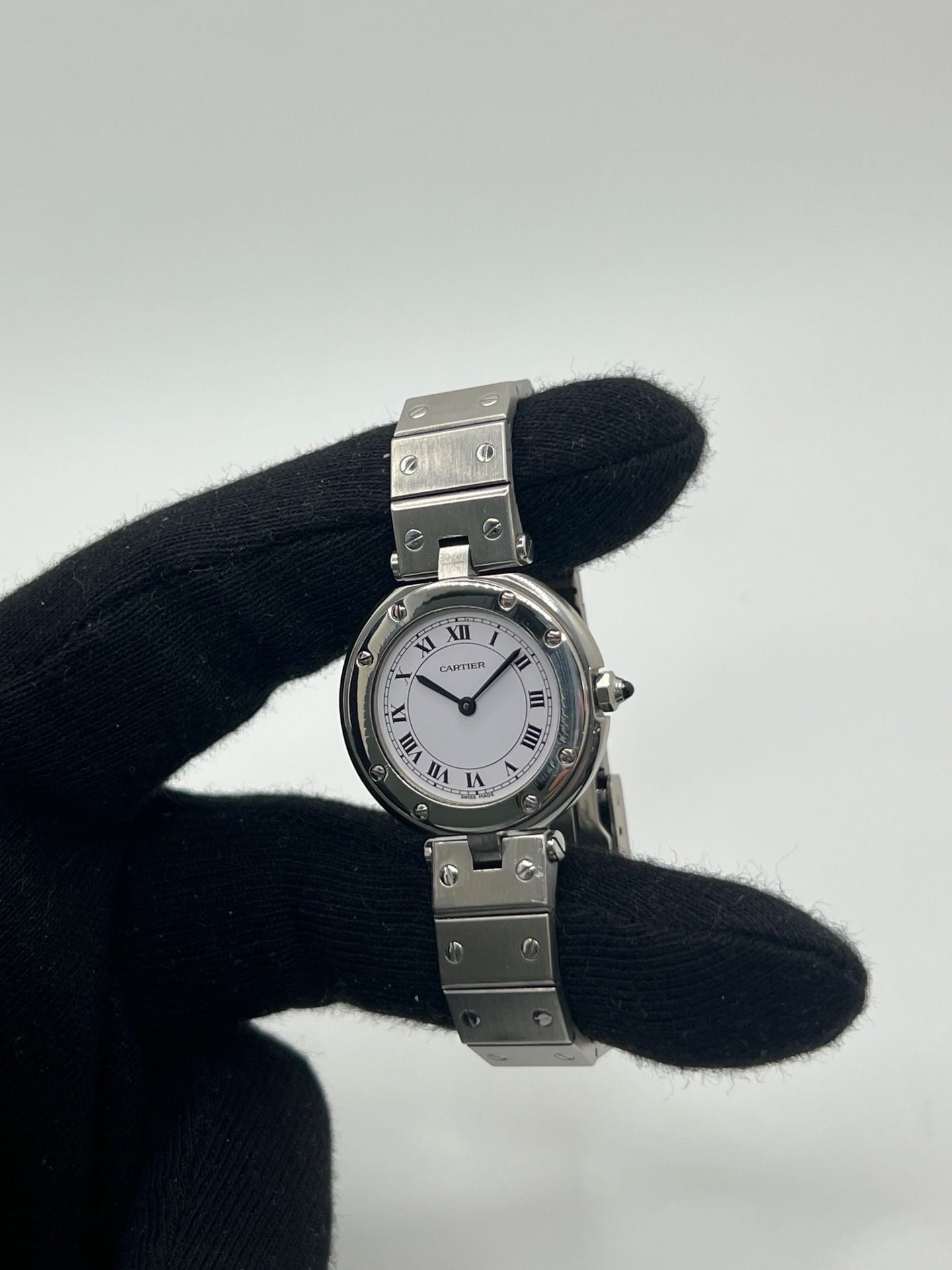 Montre Cartier Santos Vendôme référence 8192 en acier, modèle pour femme avec boîtier rond de 27 mm, cadran blanc à chiffres romains et mouvement quartz. Bracelet acier assorti, boucle à plis et verre saphir. Montre vintage de 1981 en très bon état, livrée avec coffret et papiers d’origine.