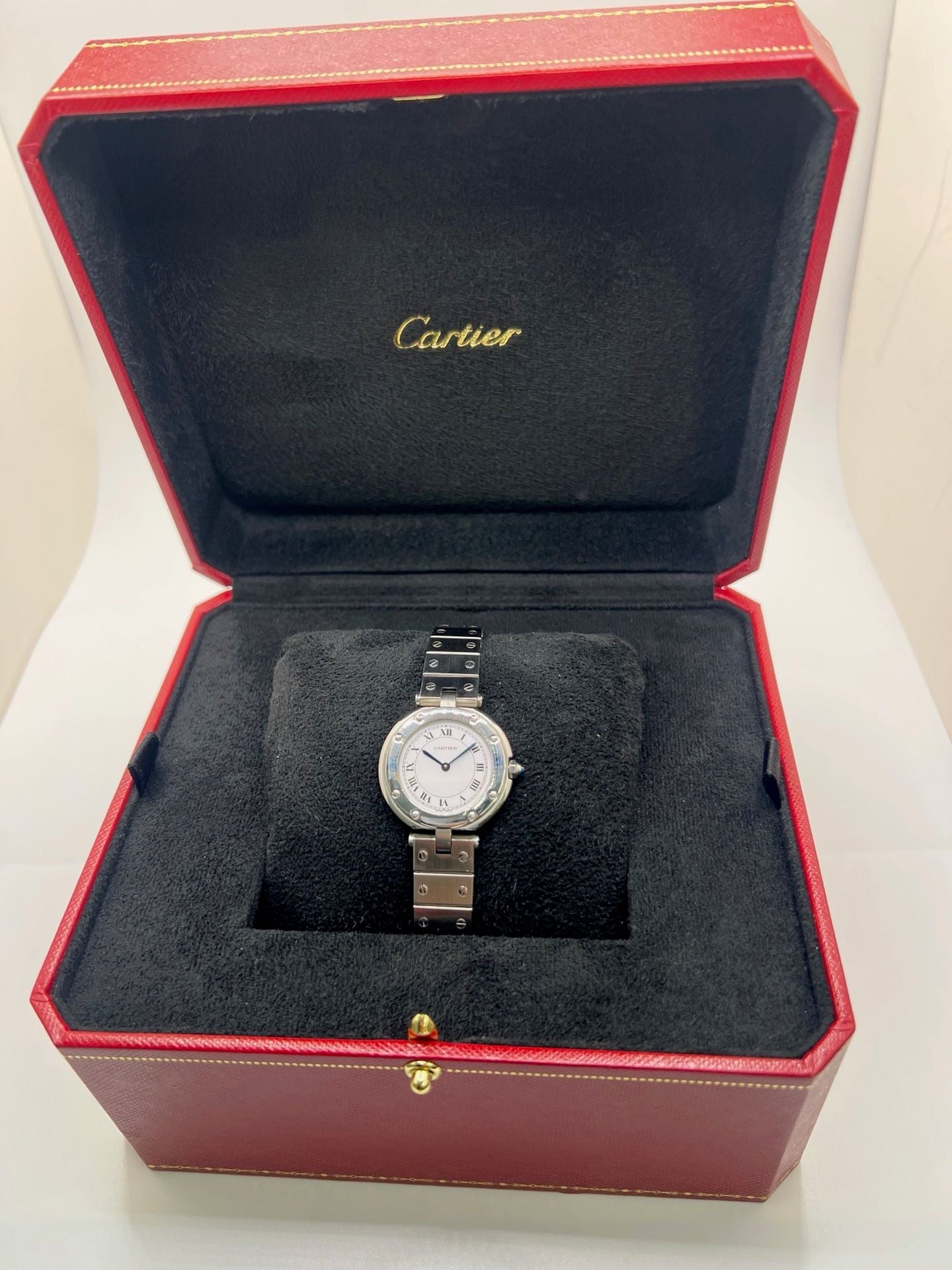 Montre Cartier Santos Vendôme référence 8192 en acier, modèle pour femme avec boîtier rond de 27 mm, cadran blanc à chiffres romains et mouvement quartz. Bracelet acier assorti, boucle à plis et verre saphir. Montre vintage de 1981 en très bon état, livrée avec coffret et papiers d’origine.
