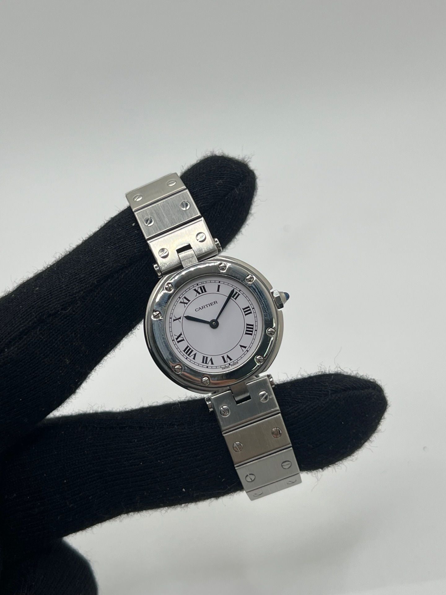 Montre Cartier Santos Vendôme référence 8192 en acier, modèle pour femme avec boîtier rond de 27 mm, cadran blanc à chiffres romains et mouvement quartz. Bracelet acier assorti, boucle à plis et verre saphir. Montre vintage de 1981 en très bon état, livrée avec coffret et papiers d’origine.