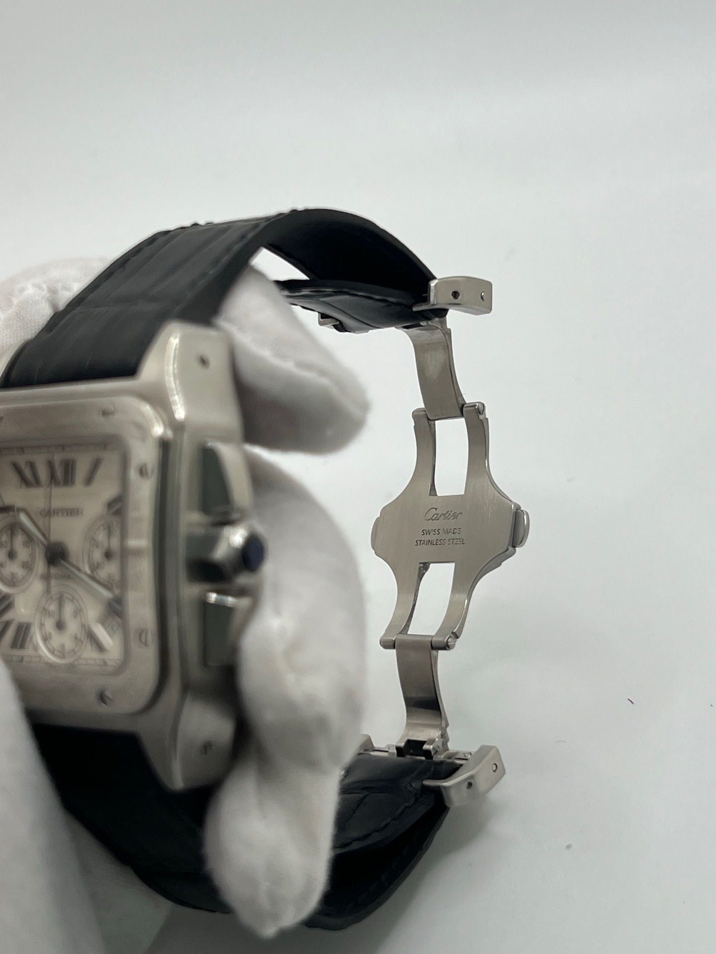 Montre Cartier Santos 100 XL Chronograph pour homme, modèle emblématique au design sport-chic. Boîtier en acier, cadran blanc à chiffres romains, bracelet en cuir noir. Mouvement automatique précis avec chronographe et date. Montre d’occasion en excellent état, révisée, livrée avec coffret d’origine.