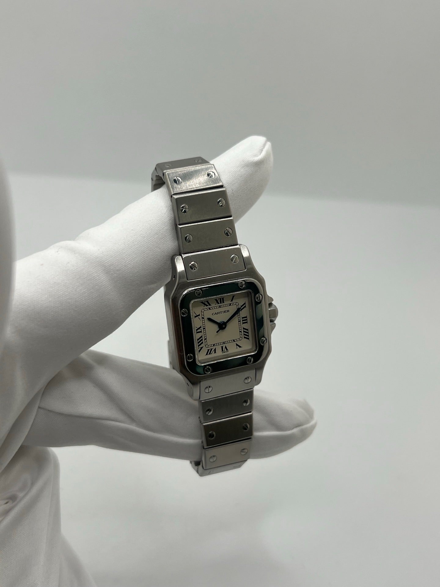Montre Cartier Santos Lady en acier pour femme, modèle vintage à remontage automatique avec cadran blanc à chiffres romains, boîtier rectangulaire 24 x 35 mm, verre saphir et bracelet acier. Cette montre d’occasion en très bon état présente de légères traces d’usure discrètes. Livrée avec son coffret d’origine, sans papiers, cette Cartier Santos Lady allie élégance intemporelle, raffinement horloger et style iconique pour une collection de montres de luxe femme.