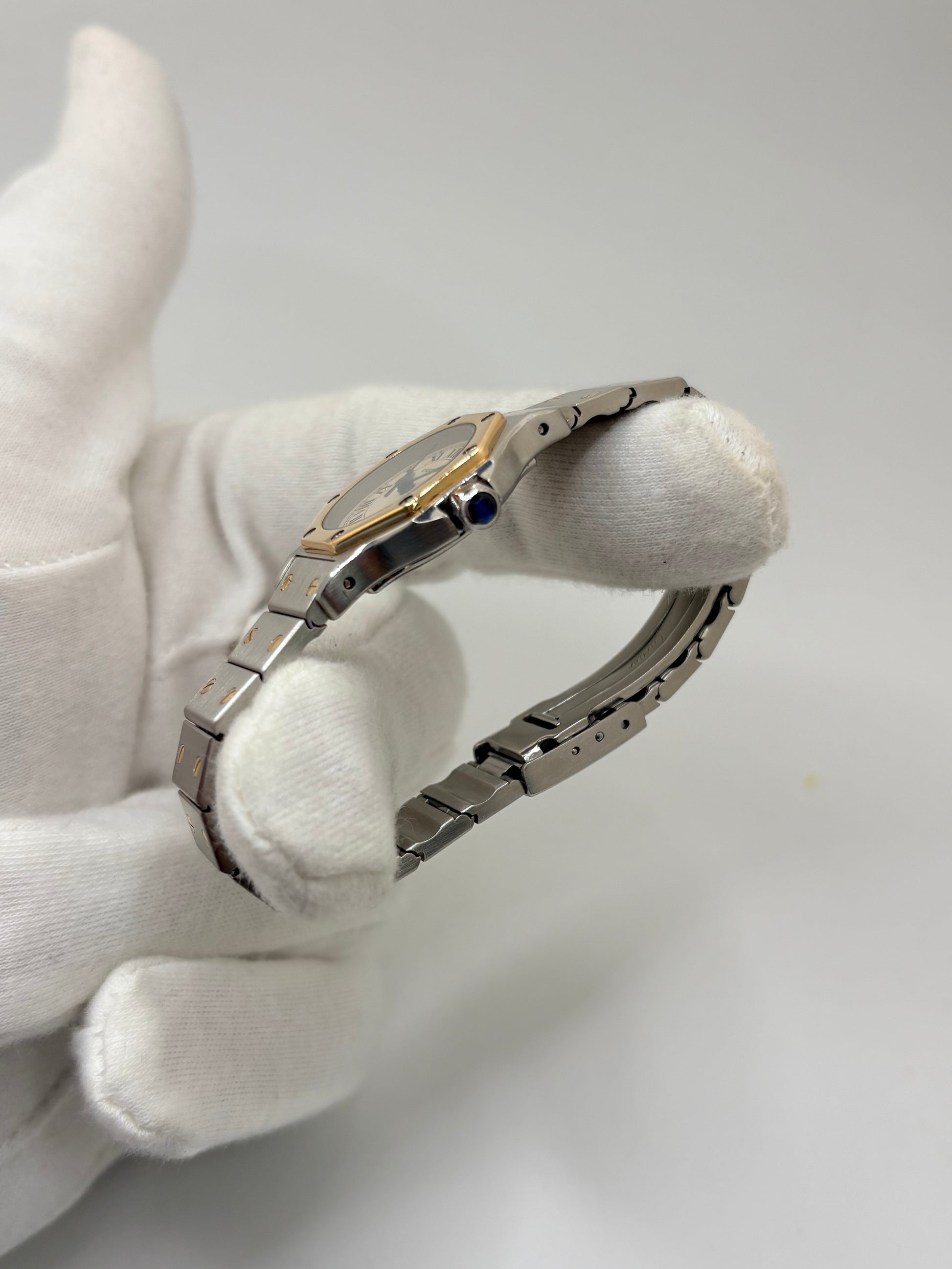 Montre Cartier Santos référence 187903 en or et acier avec boîtier de 24 x 31 mm, d'année inconnue et animée par un mouvement à quartz d'exception comptant 7 pierres. Son cadran blanc avec dateur est protégé par un verre saphir et complété par un bracelet en or et acier avec boucle pliante. Cette montre Cartier pour femme d'occasion est en très bon état, révisée en interne et livrée avec son coffret d'origine. Une pièce de luxe iconique disponible à Paris.