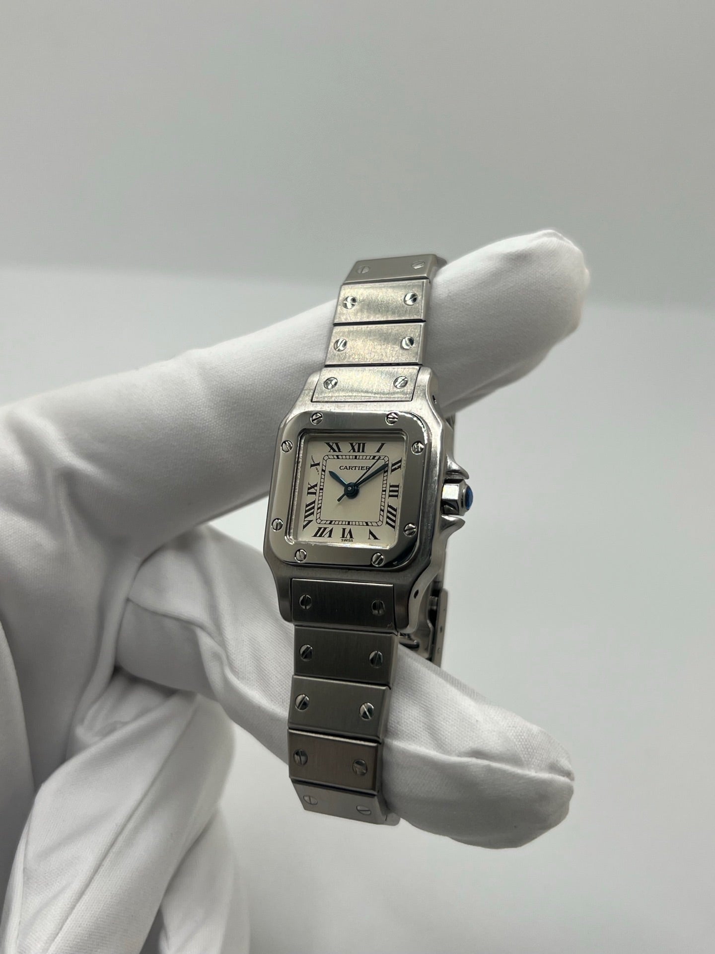 Montre Cartier Santos Lady en acier pour femme, modèle vintage à remontage automatique avec cadran blanc à chiffres romains, boîtier rectangulaire 24 x 35 mm, verre saphir et bracelet acier. Cette montre d’occasion en très bon état présente de légères traces d’usure discrètes. Livrée avec son coffret d’origine, sans papiers, cette Cartier Santos Lady allie élégance intemporelle, raffinement horloger et style iconique pour une collection de montres de luxe femme.
