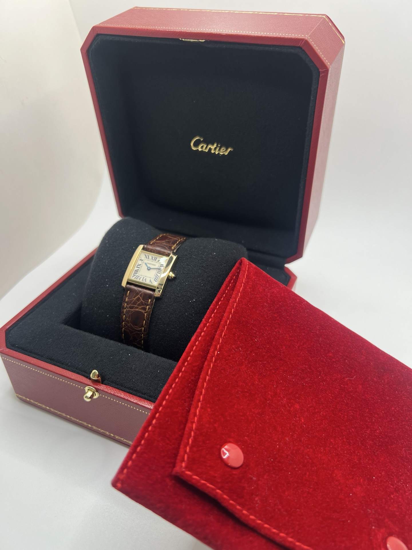 Montre Cartier Tank Française référence 1820 en or jaune 18K, petit modèle pour femme, boîtier rectangulaire emblématique aux lignes droites et élégantes, cadran blanc avec chiffres romains noirs, minuterie chemin de fer et aiguilles bleuies en forme de glaive. Bracelet intégré en acier avec boucle déployante. Mouvement quartz précis. Montre de luxe intemporelle, raffinée et iconique, idéale pour un porté quotidien ou une tenue habillée.