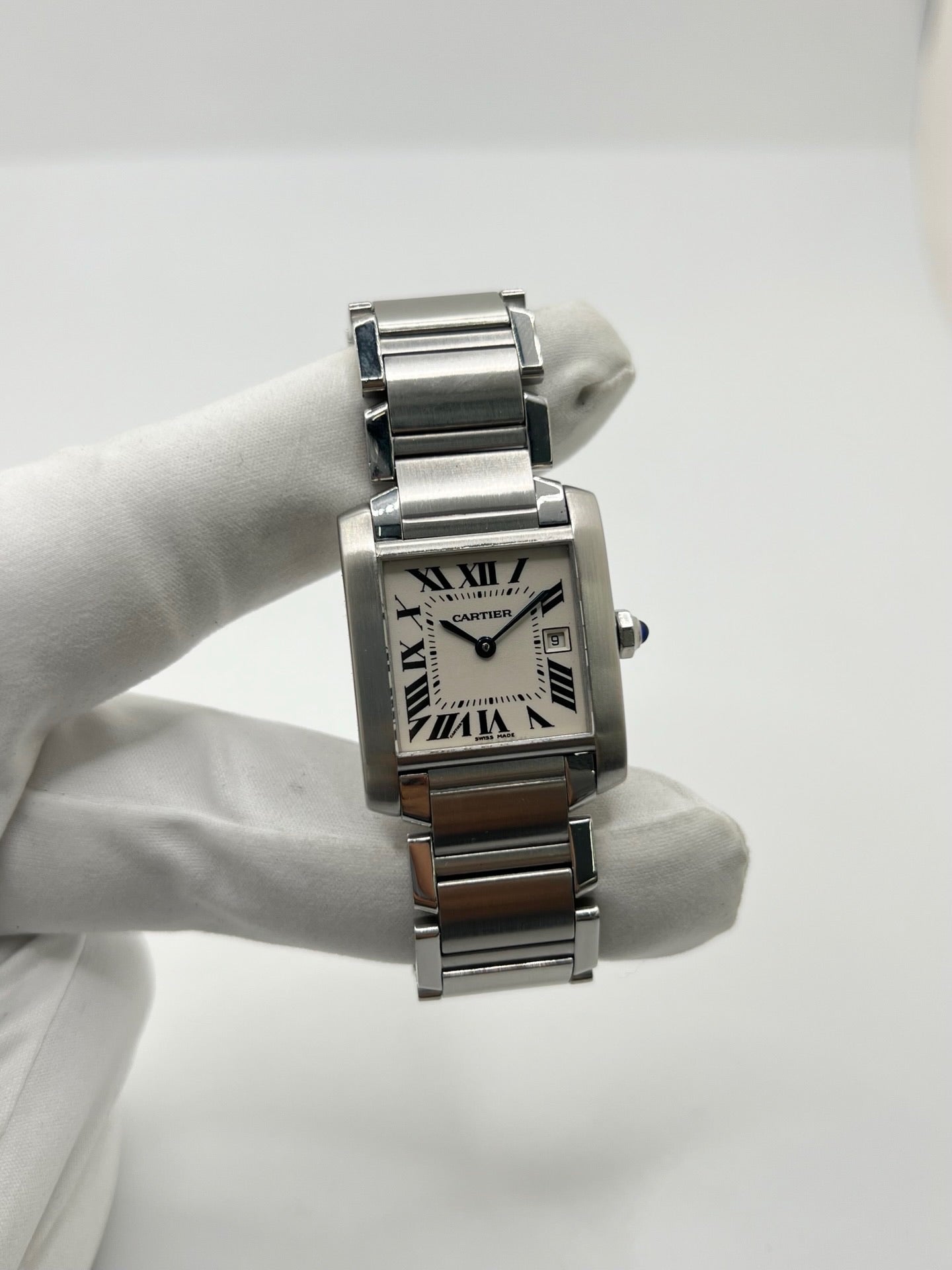Montre Cartier Tank Française 2465 pour femme en acier, dotée d’un mouvement quartz et d’un cadran blanc à chiffres romains. Ce modèle iconique présente un boîtier de 25 x 30 mm, un bracelet en acier avec boucle double plis, ainsi qu’un verre saphir. Montre de luxe d’occasion en très bon état, avec de légères traces d’usure discrètes. Livrée avec son coffret d’origine, sans papiers, révisée en interne en mars 2026.