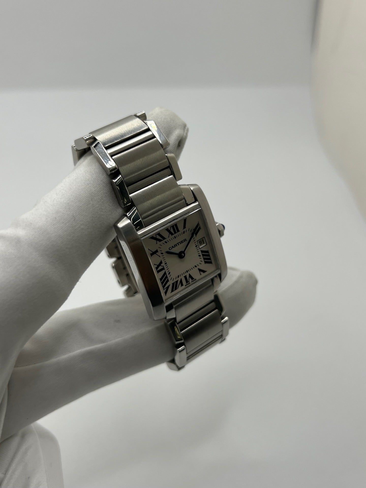 Montre Cartier Tank Française 2465 pour femme en acier, dotée d’un mouvement quartz et d’un cadran blanc à chiffres romains. Ce modèle iconique présente un boîtier de 25 x 30 mm, un bracelet en acier avec boucle double plis, ainsi qu’un verre saphir. Montre de luxe d’occasion en très bon état, avec de légères traces d’usure discrètes. Livrée avec son coffret d’origine, sans papiers, révisée en interne en mars 2026.