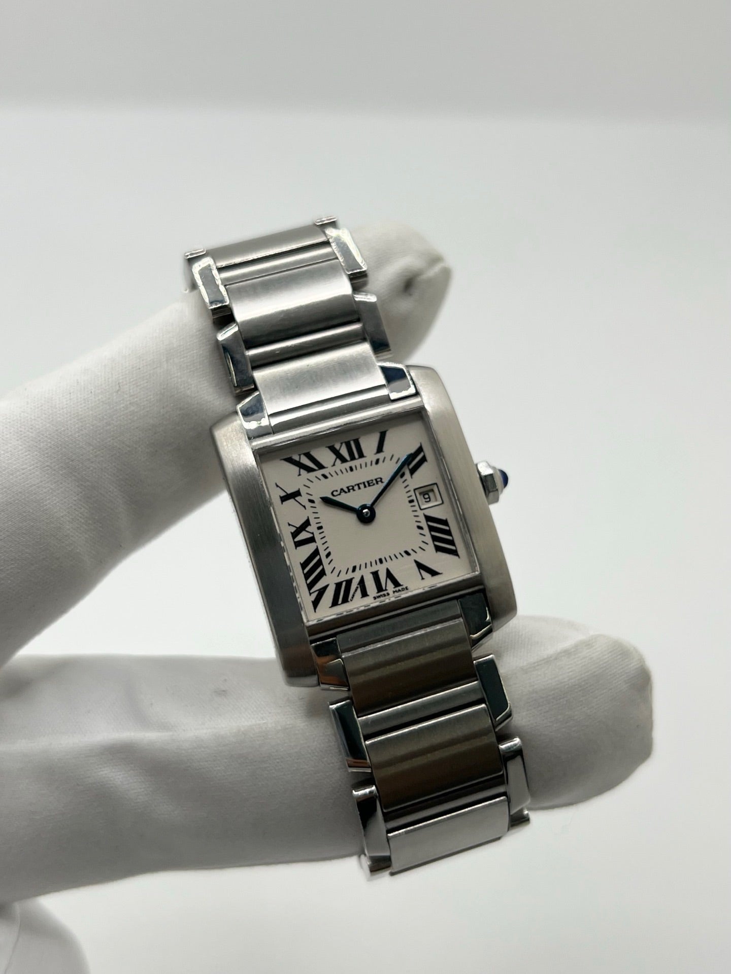 Montre Cartier Tank Française 2465 pour femme en acier, dotée d’un mouvement quartz et d’un cadran blanc à chiffres romains. Ce modèle iconique présente un boîtier de 25 x 30 mm, un bracelet en acier avec boucle double plis, ainsi qu’un verre saphir. Montre de luxe d’occasion en très bon état, avec de légères traces d’usure discrètes. Livrée avec son coffret d’origine, sans papiers, révisée en interne en mars 2026.