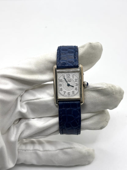 Montre Cartier Tank Must référence 2416 en argent avec cadran blanc à chiffres arabes et mouvement quartz. Ce modèle iconique présente un boîtier rectangulaire de 22 x 30 mm, une lunette en argent et un bracelet en cuir bleu avec boucle ardillon en acier. Cartier Tank Must d'occasion en très bon état, avec de légères traces d'usure. Montre homme ou unisexe élégante et intemporelle, idéale pour les amateurs d'horlogerie et de montres de luxe vintage.
