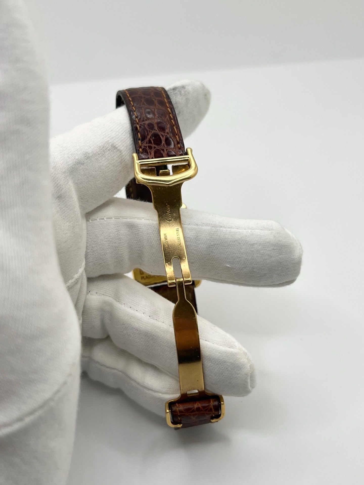 Montre Cartier Tank Must grand modèle en argent avec cadran blanc à chiffres romains, mouvement quartz et fonction date. Boîtier rectangulaire 25 x 33 mm avec verre minéral, bracelet en cuir brun et boucle ardillon en acier. Modèle iconique au design élégant et intemporel, idéal pour homme ou unisexe. Montre d’occasion en bon état, révisée, avec coffret d’origine.