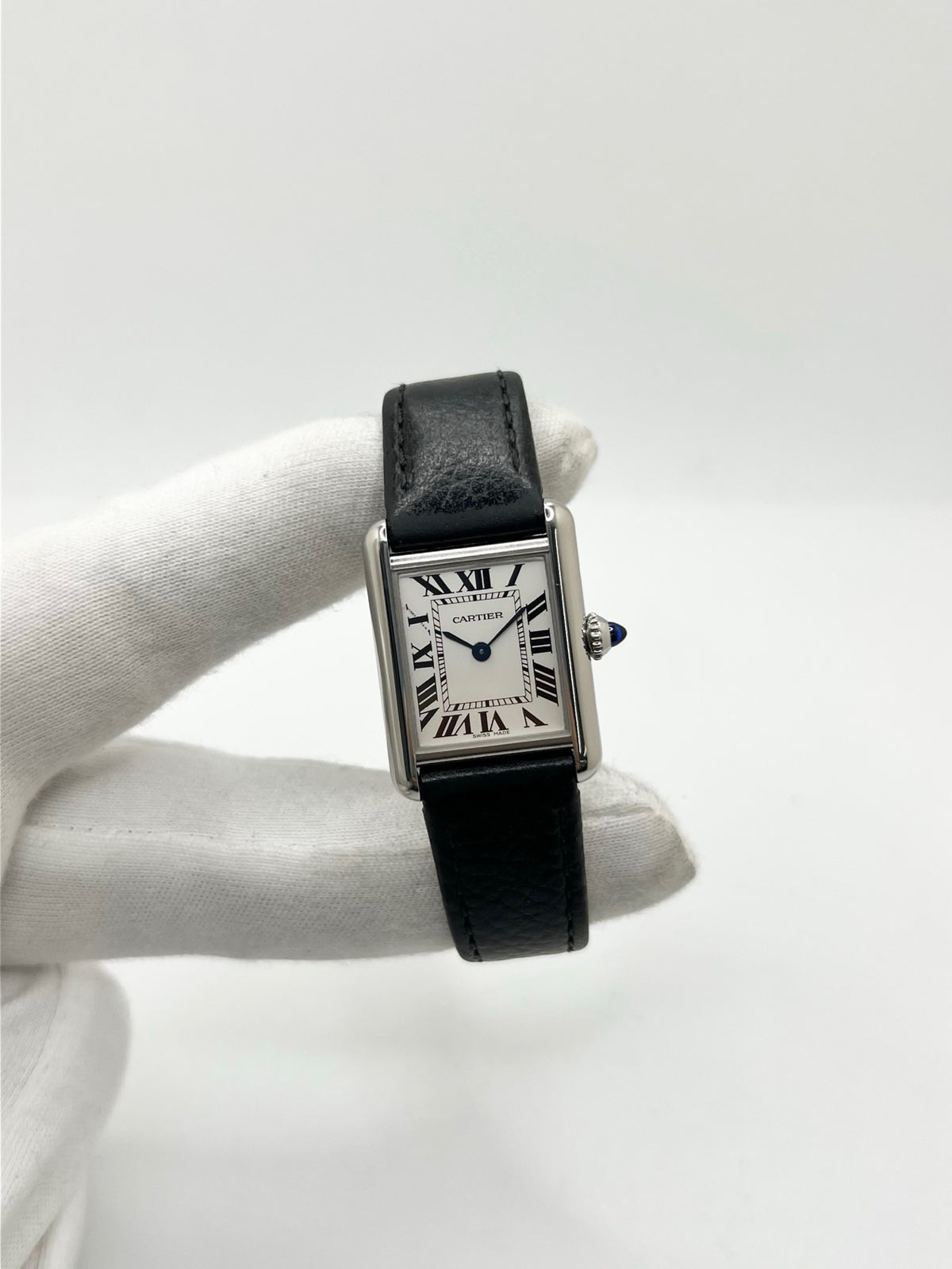 Montre Cartier Tank Must PM WSTA0042 pour femme, modèle élégant de la collection Tank datant de 2021. Cette montre de luxe se distingue par son boîtier rectangulaire en acier de 22 x 29 mm, son cadran argenté, son verre saphir et son bracelet en cuir noir. Équipée d’un mouvement à quartz, la Cartier Tank Must PM allie sobriété et élégance intemporelle. Proposée d’occasion en très bon état, elle est vendue avec son coffret d’origine et a bénéficié d’une révision interne le 19 octobre 2026.