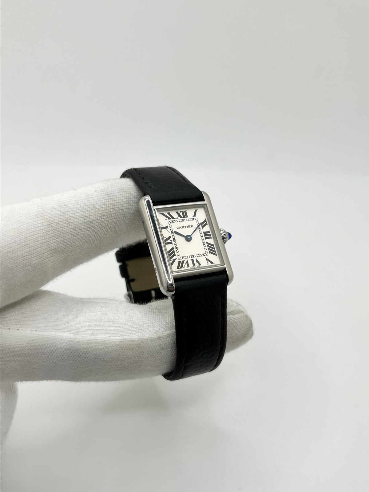 Montre Cartier Tank Must PM WSTA0042 pour femme, modèle élégant de la collection Tank datant de 2021. Cette montre de luxe se distingue par son boîtier rectangulaire en acier de 22 x 29 mm, son cadran argenté, son verre saphir et son bracelet en cuir noir. Équipée d’un mouvement à quartz, la Cartier Tank Must PM allie sobriété et élégance intemporelle. Proposée d’occasion en très bon état, elle est vendue avec son coffret d’origine et a bénéficié d’une révision interne le 19 octobre 2026.