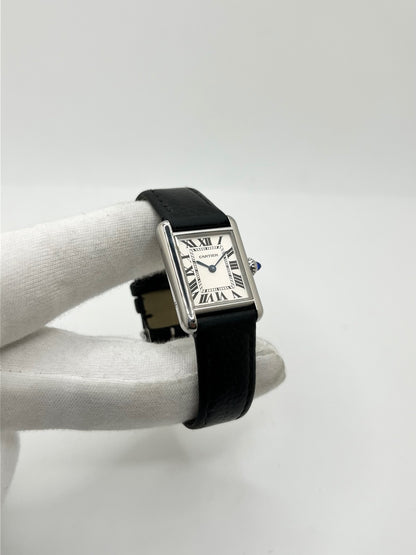 Montre Cartier Tank Must PM WSTA0042 pour femme, modèle élégant de la collection Tank datant de 2021. Cette montre de luxe se distingue par son boîtier rectangulaire en acier de 22 x 29 mm, son cadran argenté, son verre saphir et son bracelet en cuir noir. Équipée d’un mouvement à quartz, la Cartier Tank Must PM allie sobriété et élégance intemporelle. Proposée d’occasion en très bon état, elle est vendue avec son coffret d’origine et a bénéficié d’une révision interne le 19 octobre 2026.