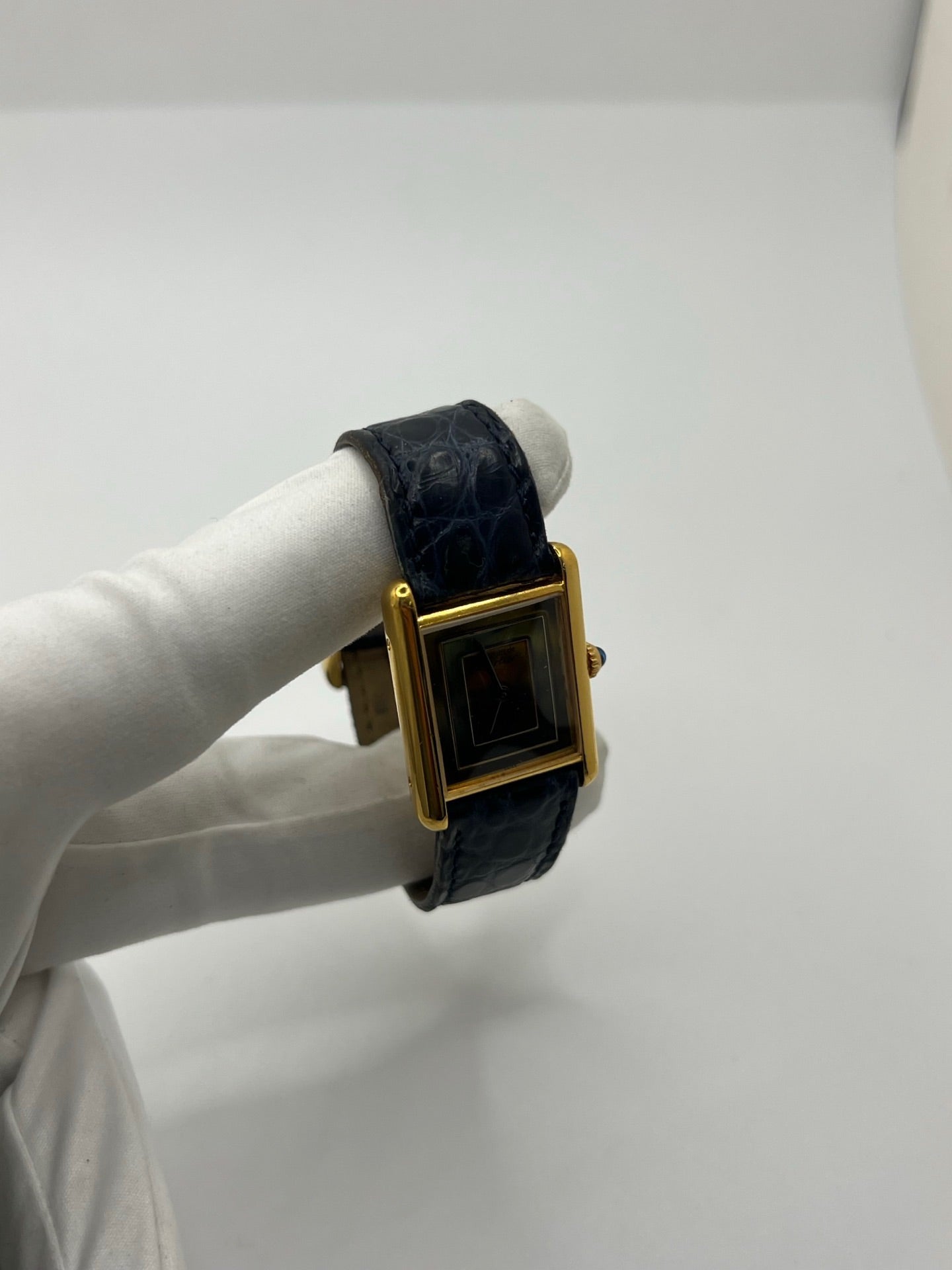 Montre Cartier Must de Cartier Tank Trinity en argent, à remontage manuel, avec boîtier de 23 x 30 mm et cadran jaune sans chiffres. Ce modèle emblématique est équipé d’un bracelet en cuir bleu avec boucle ardillon en acier, d’un verre minéral et d’une lunette en argent. Montre de luxe vintage homme ou unisexe, d’occasion en bon état, présentant des traces d’usure visibles. Révisée en interne, livrée avec coffret d’origine, idéale pour les collectionneurs de montres Cartier Tank Trinity.