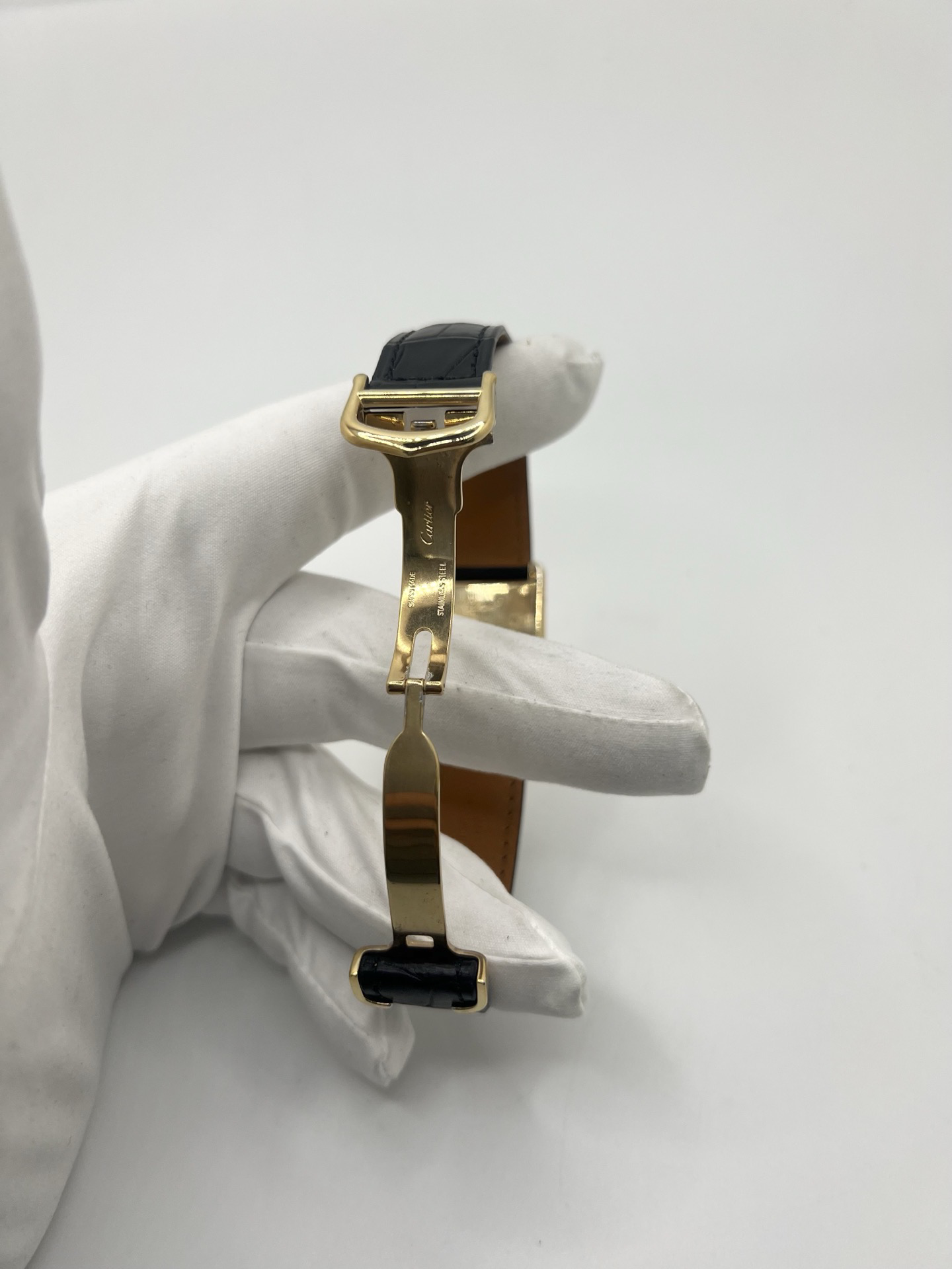 Montre Cartier Tank Must Trinity Grand Modèle vintage en vermeil, référence 590005, datant des années 1990. Boîtier rectangulaire de 23 x 30 mm en argent vermeil, cadran blanc à chiffres romains avec motif Trinity emblématique, verre saphir et mouvement quartz Cartier calibre 90. Bracelet en cuir avec boucle Cartier. Cette montre de luxe au design intemporel incarne l’élégance française et l’héritage horloger de Cartier, recherchée par les collectionneurs de montres vintage.