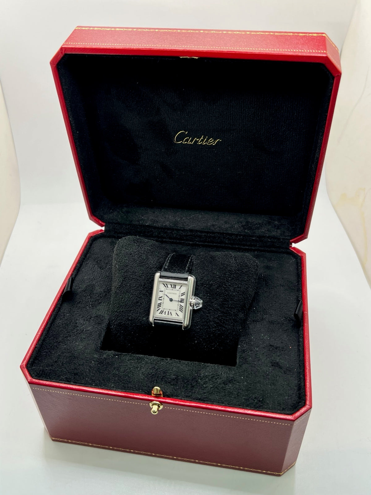 Montre Cartier Tank Must PM WSTA0042 pour femme, modèle élégant de la collection Tank datant de 2021. Cette montre de luxe se distingue par son boîtier rectangulaire en acier de 22 x 29 mm, son cadran argenté, son verre saphir et son bracelet en cuir noir. Équipée d’un mouvement à quartz, la Cartier Tank Must PM allie sobriété et élégance intemporelle. Proposée d’occasion en très bon état, elle est vendue avec son coffret d’origine et a bénéficié d’une révision interne le 19 octobre 2026.