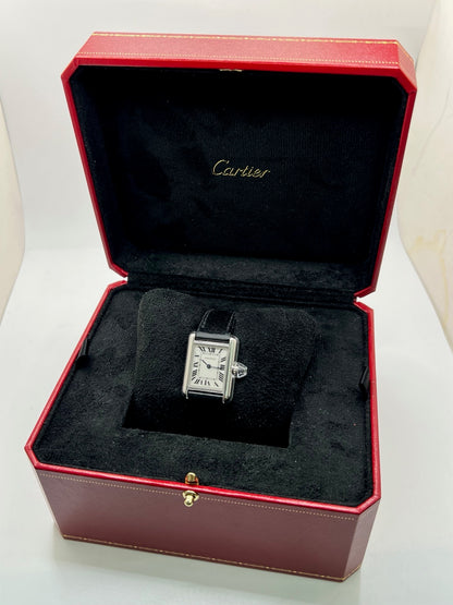 Montre Cartier Tank Must PM WSTA0042 pour femme, modèle élégant de la collection Tank datant de 2021. Cette montre de luxe se distingue par son boîtier rectangulaire en acier de 22 x 29 mm, son cadran argenté, son verre saphir et son bracelet en cuir noir. Équipée d’un mouvement à quartz, la Cartier Tank Must PM allie sobriété et élégance intemporelle. Proposée d’occasion en très bon état, elle est vendue avec son coffret d’origine et a bénéficié d’une révision interne le 19 octobre 2026.