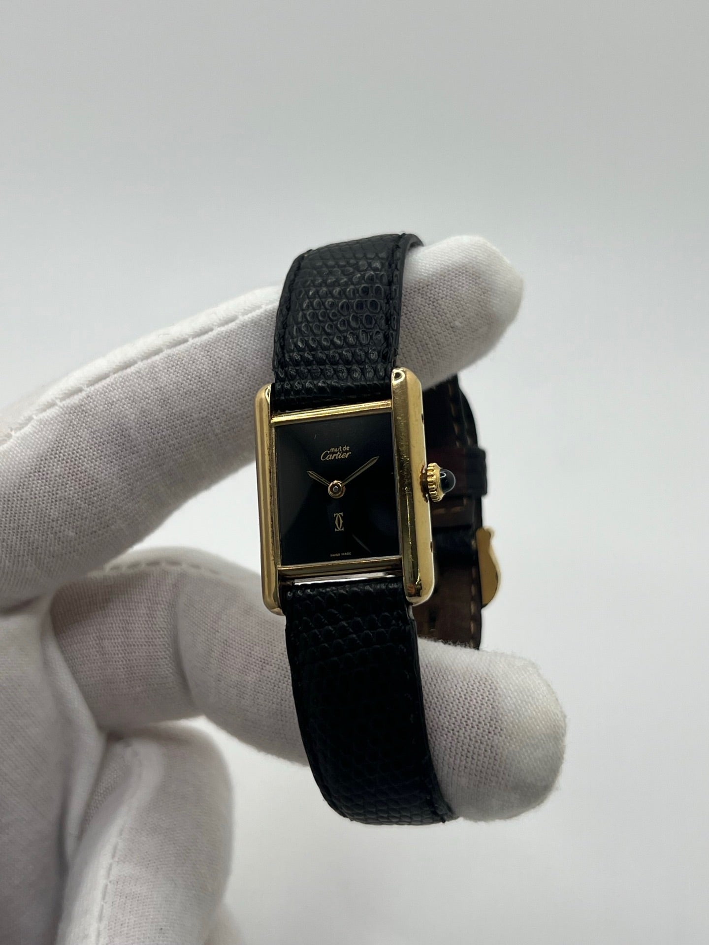 Montre Cartier Tank Must Vermeil référence 5057001 pour femme, boîtier en argent 20 x 28 mm, cadran noir sans chiffres et bracelet en cuir de lézard noir. Modèle à mouvement quartz, en bon état avec traces d’usure légères. Montre élégante au style intemporel, idéale pour un look sophistiqué et raffiné. Parfaite pour les amateurs de pièces vintage.