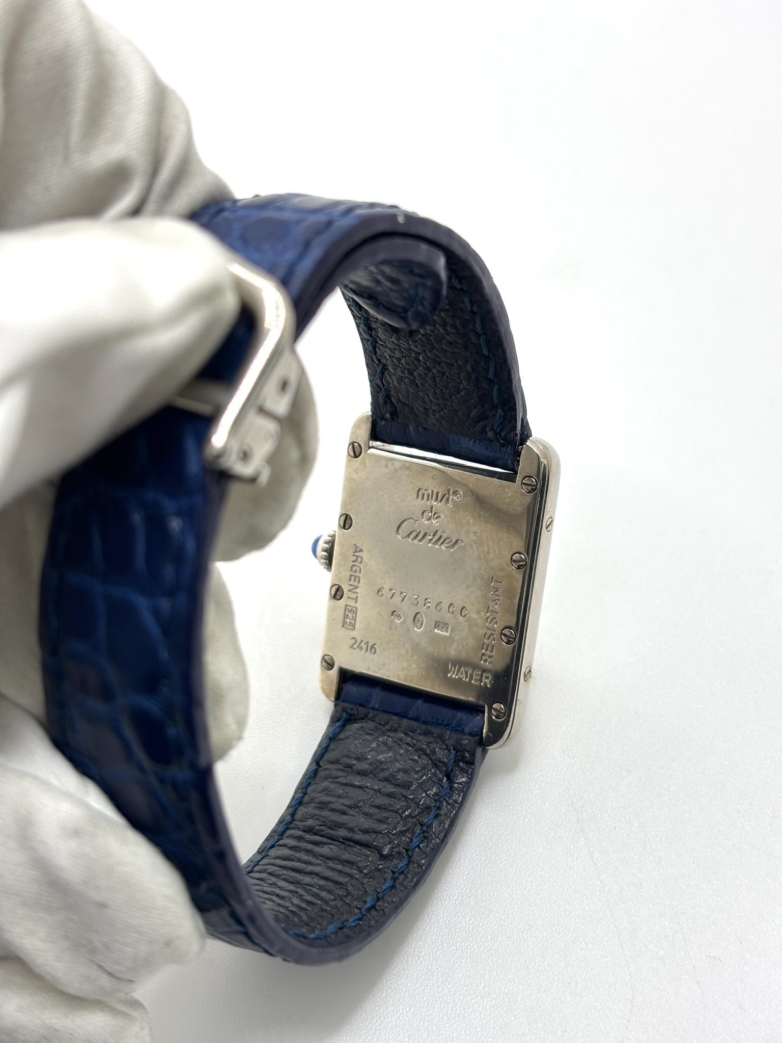 Montre Cartier Tank Must référence 2416 en argent avec cadran blanc à chiffres arabes et mouvement quartz. Ce modèle iconique présente un boîtier rectangulaire de 22 x 30 mm, une lunette en argent et un bracelet en cuir bleu avec boucle ardillon en acier. Cartier Tank Must d'occasion en très bon état, avec de légères traces d'usure. Montre homme ou unisexe élégante et intemporelle, idéale pour les amateurs d'horlogerie et de montres de luxe vintage.
