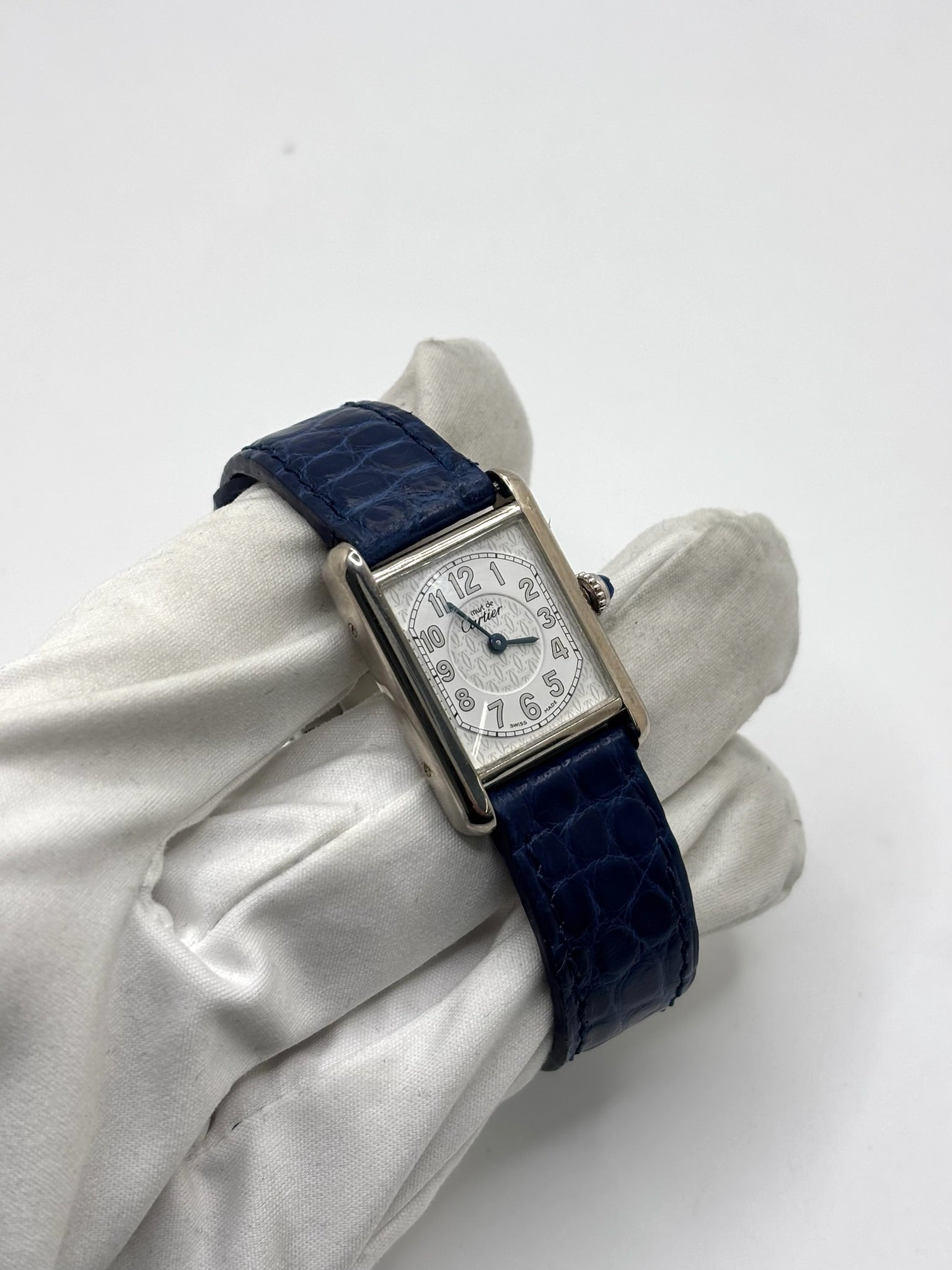 Montre Cartier Tank Must référence 2416 en argent avec cadran blanc à chiffres arabes et mouvement quartz. Ce modèle iconique présente un boîtier rectangulaire de 22 x 30 mm, une lunette en argent et un bracelet en cuir bleu avec boucle ardillon en acier. Cartier Tank Must d'occasion en très bon état, avec de légères traces d'usure. Montre homme ou unisexe élégante et intemporelle, idéale pour les amateurs d'horlogerie et de montres de luxe vintage.
