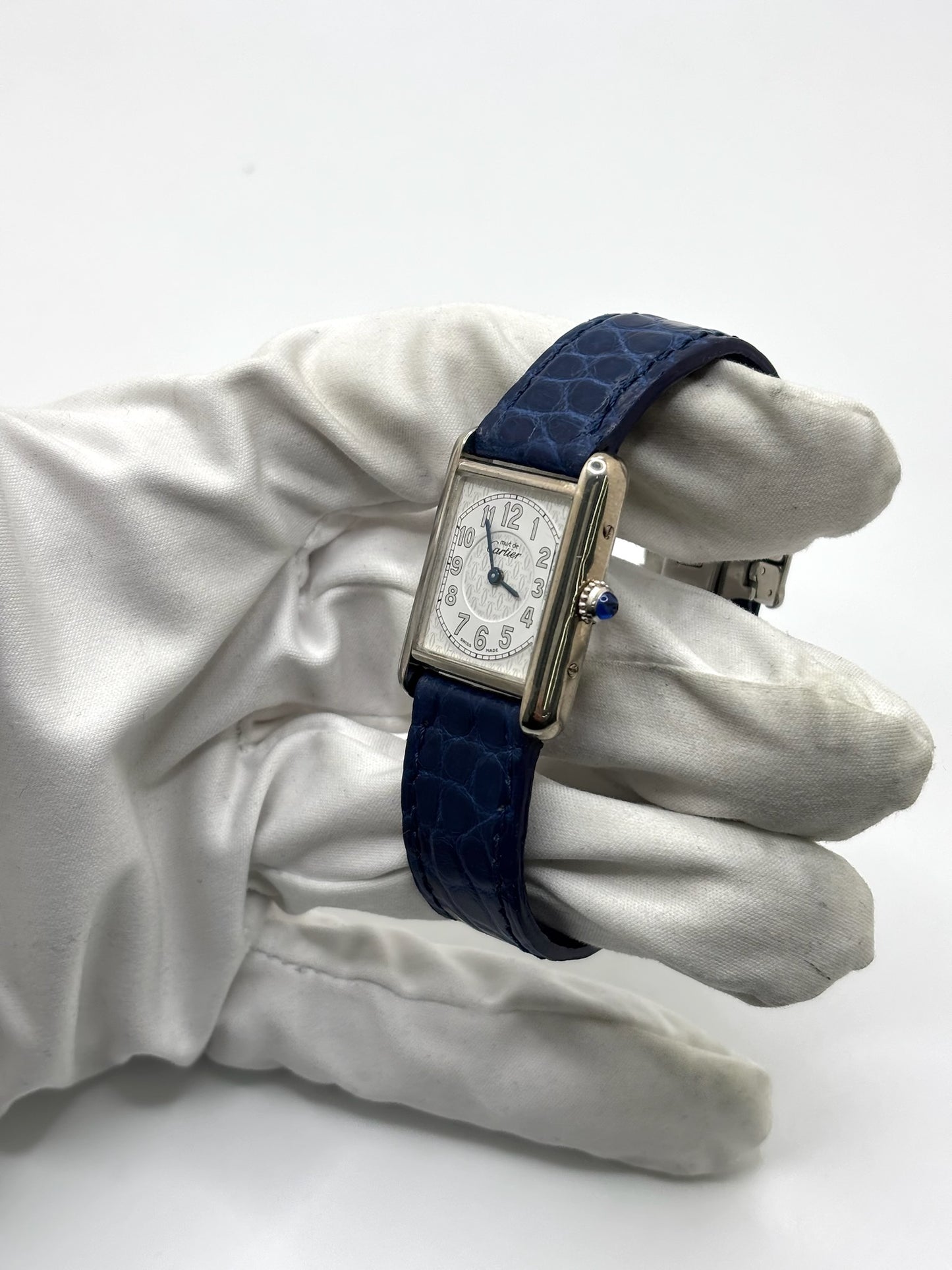 Montre Cartier Tank Must référence 2416 en argent avec cadran blanc à chiffres arabes et mouvement quartz. Ce modèle iconique présente un boîtier rectangulaire de 22 x 30 mm, une lunette en argent et un bracelet en cuir bleu avec boucle ardillon en acier. Cartier Tank Must d'occasion en très bon état, avec de légères traces d'usure. Montre homme ou unisexe élégante et intemporelle, idéale pour les amateurs d'horlogerie et de montres de luxe vintage.
