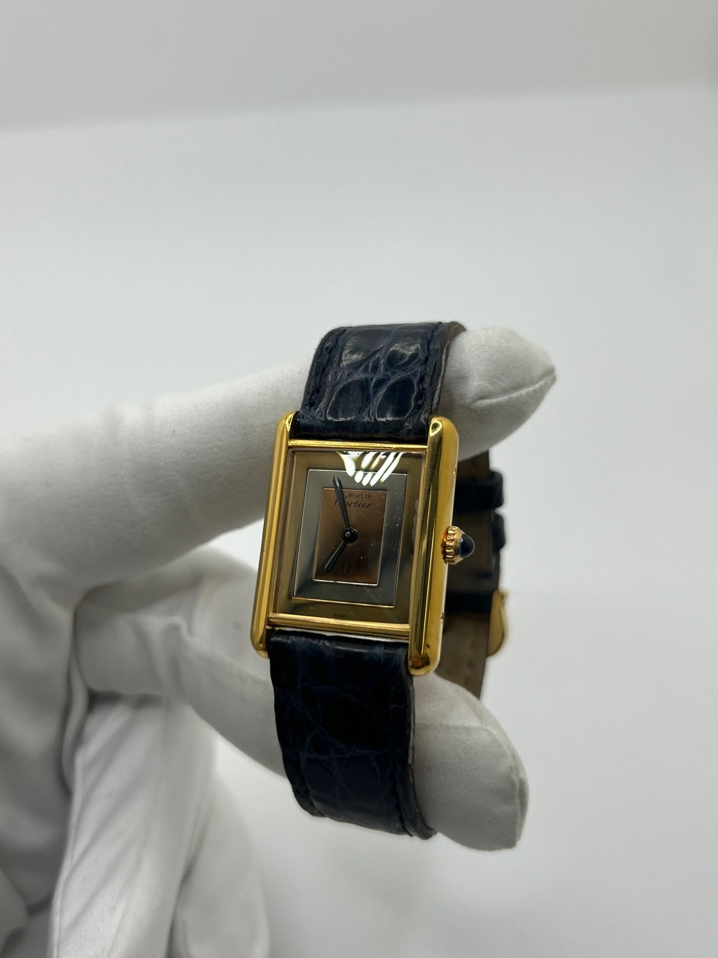Montre Cartier Must de Cartier Tank Trinity en argent, à remontage manuel, avec boîtier de 23 x 30 mm et cadran jaune sans chiffres. Ce modèle emblématique est équipé d’un bracelet en cuir bleu avec boucle ardillon en acier, d’un verre minéral et d’une lunette en argent. Montre de luxe vintage homme ou unisexe, d’occasion en bon état, présentant des traces d’usure visibles. Révisée en interne, livrée avec coffret d’origine, idéale pour les collectionneurs de montres Cartier Tank Trinity.