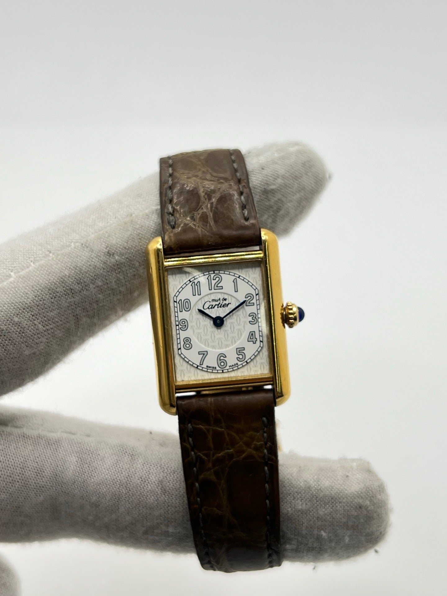 Montre Cartier Tank Vermeil 2415 pour femme, équipée d’un mouvement quartz et d’un boîtier en argent de 22 x 29 mm. Ce modèle d’occasion en bon état présente des traces d’usure visibles, un cadran blanc à chiffres arabes, un verre minéral et un bracelet en cuir brun avec boucle ardillon en argent. Élégante et classique, la Cartier Tank Vermeil 2415 séduit par son design intemporel, idéale pour les passionnées de montres de luxe.