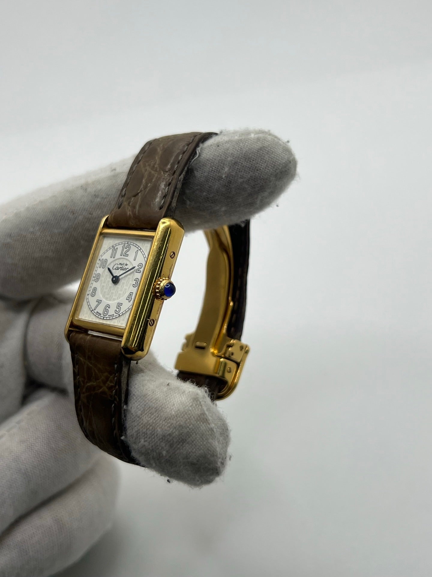 Montre Cartier Tank Vermeil 2415 pour femme, équipée d’un mouvement quartz et d’un boîtier en argent de 22 x 29 mm. Ce modèle d’occasion en bon état présente des traces d’usure visibles, un cadran blanc à chiffres arabes, un verre minéral et un bracelet en cuir brun avec boucle ardillon en argent. Élégante et classique, la Cartier Tank Vermeil 2415 séduit par son design intemporel, idéale pour les passionnées de montres de luxe.