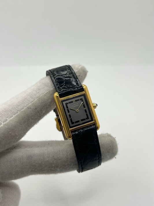 Montre Cartier Tank Vermeil 3 66001 pour femme, équipée d’un mouvement quartz et d’un boîtier en argent de 20 x 27 mm. Ce modèle d’occasion en très bon état présente un cadran or à chiffres romains, un verre minéral et un bracelet en cuir de crocodile noir avec boucle en acier. Élégante et intemporelle, la Cartier Tank Vermeil 3 66001 séduit par son design classique, idéale pour les passionnées de montres de luxe raffinées.