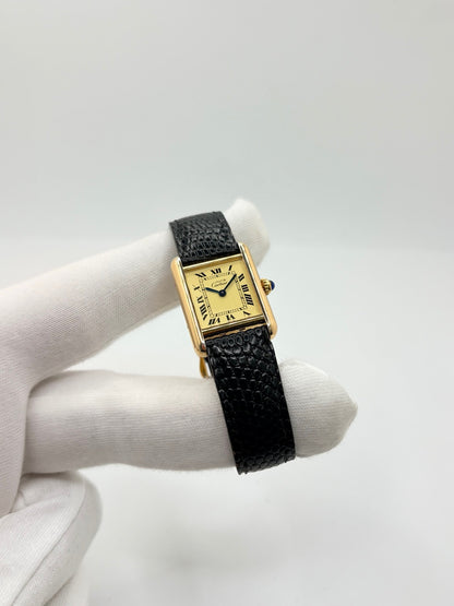 Montre Cartier Tank Vermeil 5057001 en très bon état, équipée d’un mouvement quartz et d’un boîtier en argent de 20 × 28 mm. Son cadran blanc à chiffres romains est protégé par un verre minéral. Cette montre Cartier Tank Vermeil possède un bracelet en cuir de lézard noir avec boucle ardillon en acier. Livrée avec son coffret d’origine, elle séduit par son design élégant et intemporel, emblématique de la collection Tank.