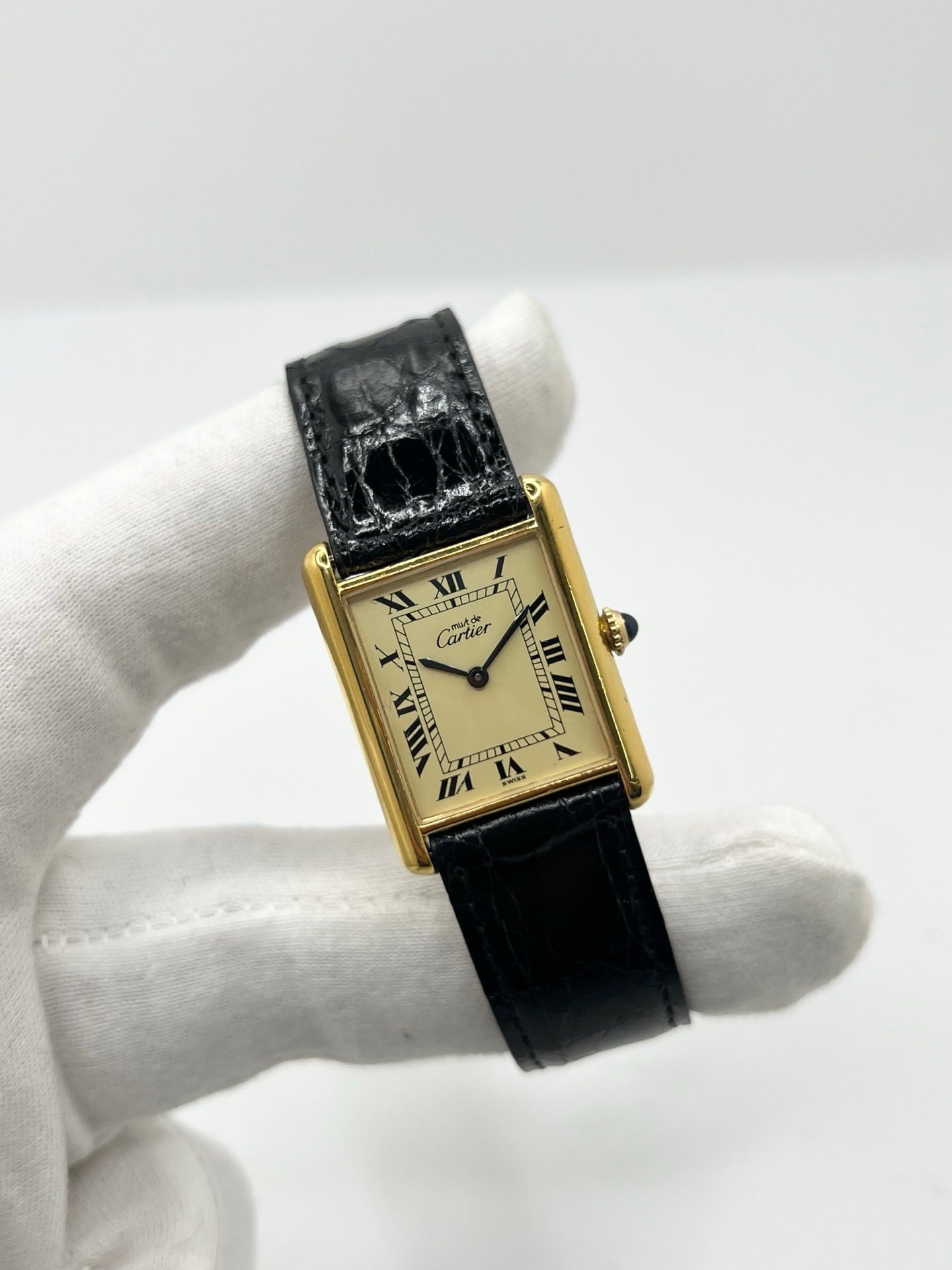 Montre Cartier Tank Vermeil mécanique vintage en argent plaqué or, dotée d’un mouvement à remontage manuel. Ce modèle emblématique présente un cadran champagne à chiffres romains, un boîtier rectangulaire de 23 x 30 mm et un bracelet en cuir de crocodile noir avec boucle ardillon en acier. Élégante et intemporelle, cette montre Cartier Must Tank d’occasion en très bon état séduit les amateurs d’horlogerie classique et de montres de luxe vintage.
