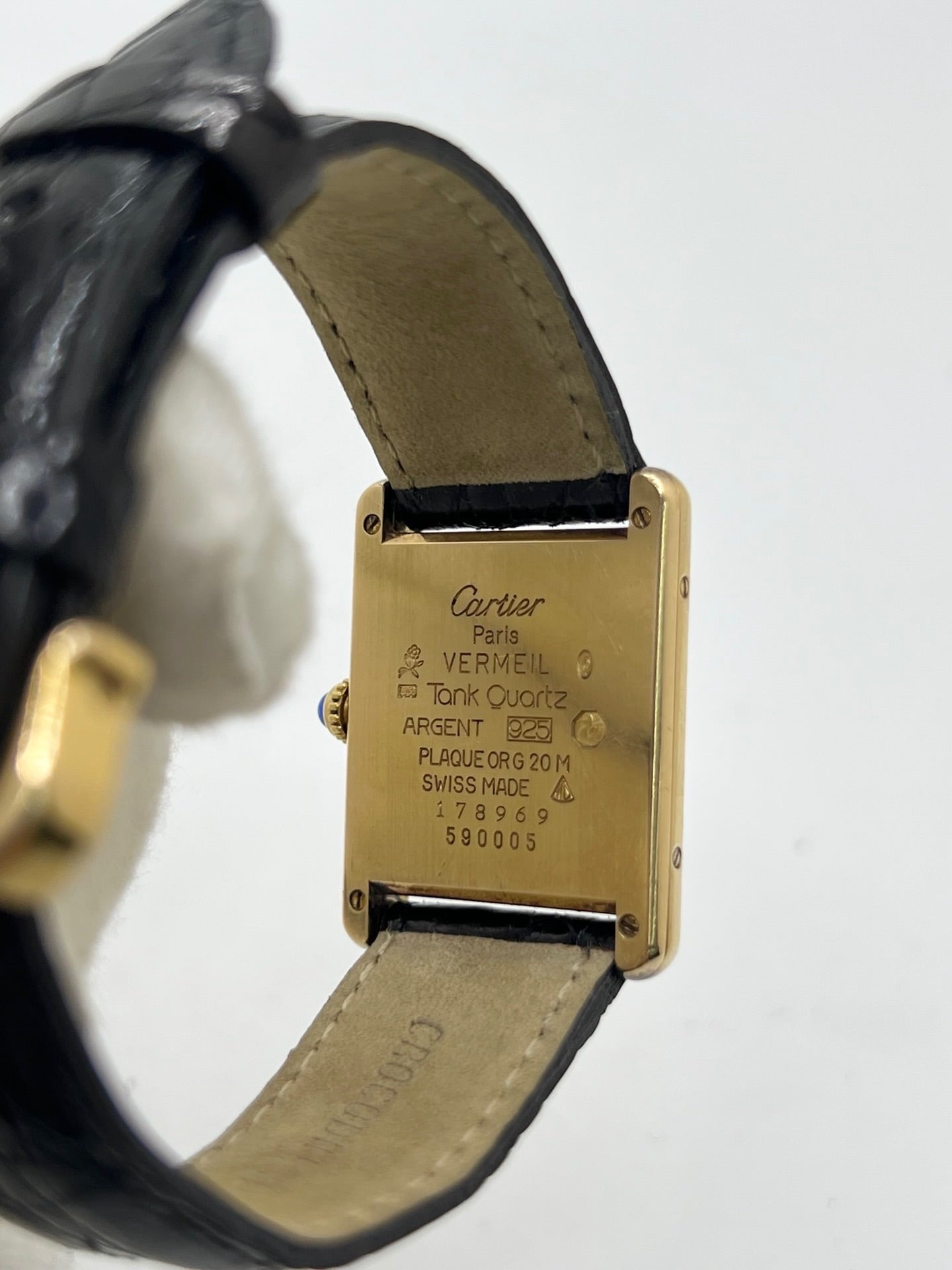 Montre Cartier Tank Vermeil réf. 590005 en argent avec mouvement à quartz, cadran champagne à chiffres romains et verre saphir. Ce modèle emblématique est monté sur un bracelet en cuir de crocodile noir avec boucle ardillon en acier. Son boîtier de 23 × 30 mm offre une élégance intemporelle. Cette montre Cartier Tank Vermeil d'occasion est en très bon état, révisée en interne et livrée avec son coffret d'origine.