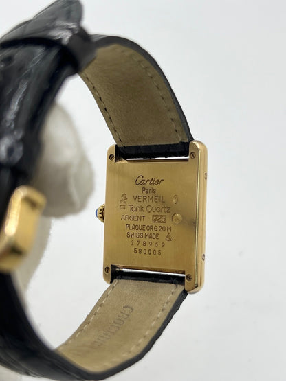 Montre Cartier Tank Vermeil réf. 590005 en argent avec mouvement à quartz, cadran champagne à chiffres romains et verre saphir. Ce modèle emblématique est monté sur un bracelet en cuir de crocodile noir avec boucle ardillon en acier. Son boîtier de 23 × 30 mm offre une élégance intemporelle. Cette montre Cartier Tank Vermeil d'occasion est en très bon état, révisée en interne et livrée avec son coffret d'origine.