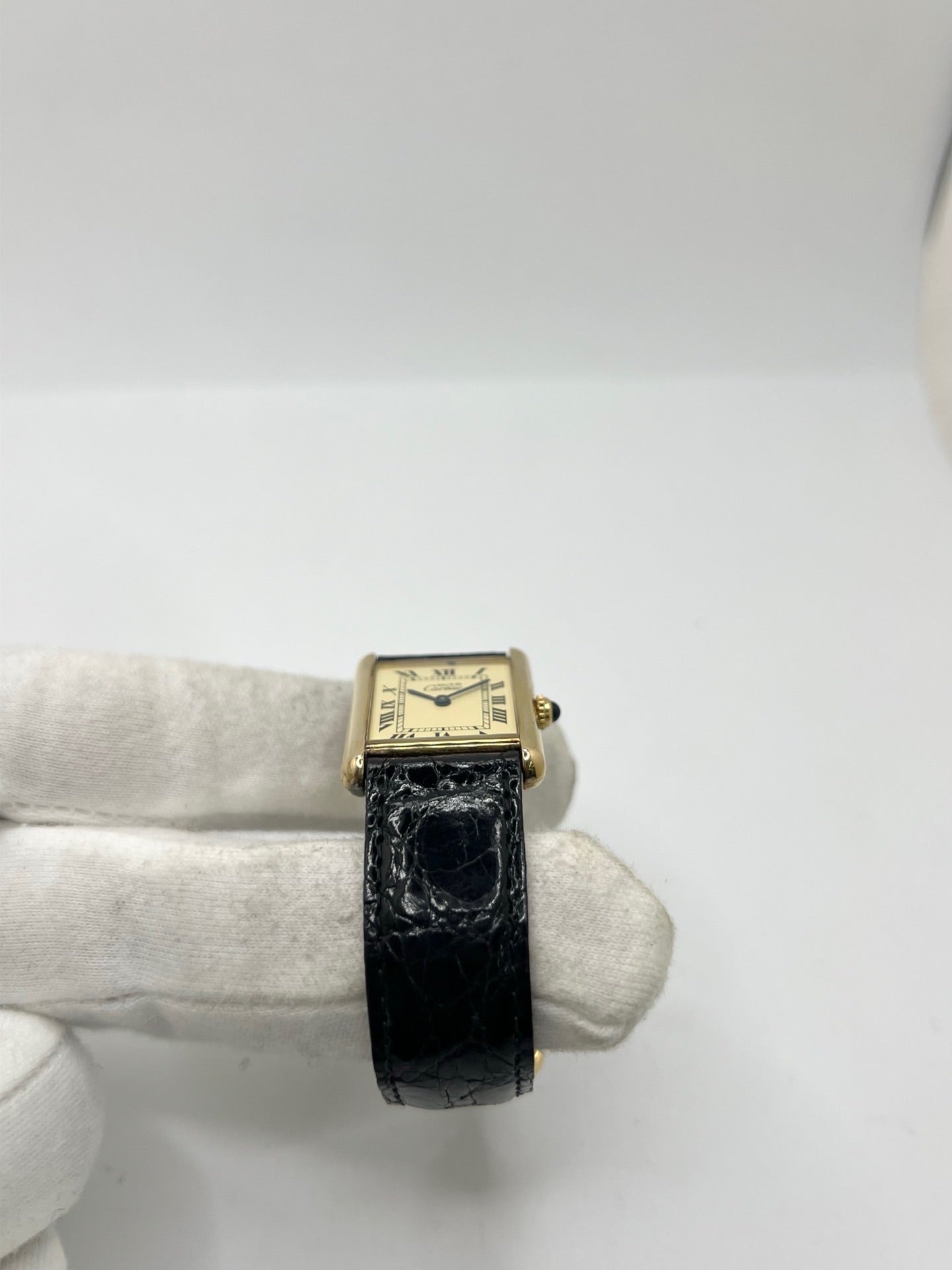Montre Cartier Tank Vermeil réf. 590005 en argent avec mouvement à quartz, cadran champagne à chiffres romains et verre saphir. Ce modèle emblématique est monté sur un bracelet en cuir de crocodile noir avec boucle ardillon en acier. Son boîtier de 23 × 30 mm offre une élégance intemporelle. Cette montre Cartier Tank Vermeil d'occasion est en très bon état, révisée en interne et livrée avec son coffret d'origine.
