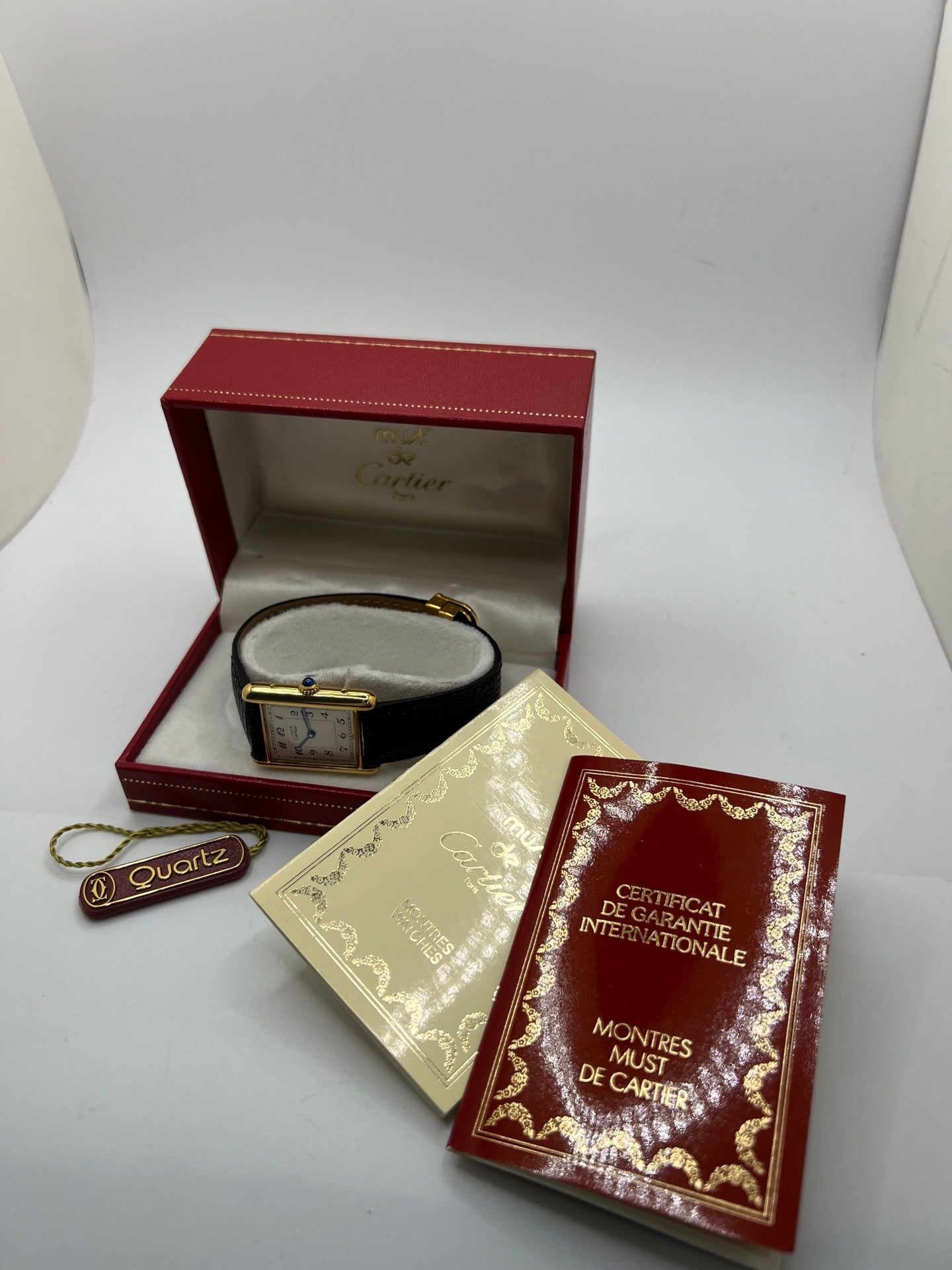 Montre Cartier Tank Vermeil référence 590005 vintage de 1989, avec boîtier rectangulaire en argent aux proportions classiques 23 x 30 mm, cadran argenté élégant avec chiffres arabes noirs et aiguilles bleuies, verre saphir et mouvement quartz. Montée sur un bracelet en cuir de lézard noir avec boucle ardillon en acier. Modèle iconique au design intemporel, livré avec son coffret et ses papiers d’origine, en très bon état.