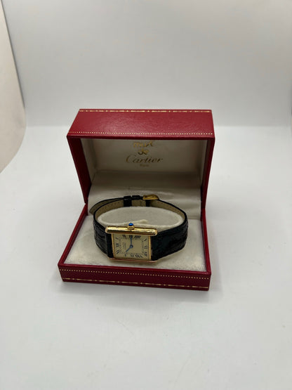 Montre Cartier Tank Vermeil réf. 590005 en argent avec mouvement à quartz, cadran champagne à chiffres romains et verre saphir. Ce modèle emblématique est monté sur un bracelet en cuir de crocodile noir avec boucle ardillon en acier. Son boîtier de 23 × 30 mm offre une élégance intemporelle. Cette montre Cartier Tank Vermeil d'occasion est en très bon état, révisée en interne et livrée avec son coffret d'origine.