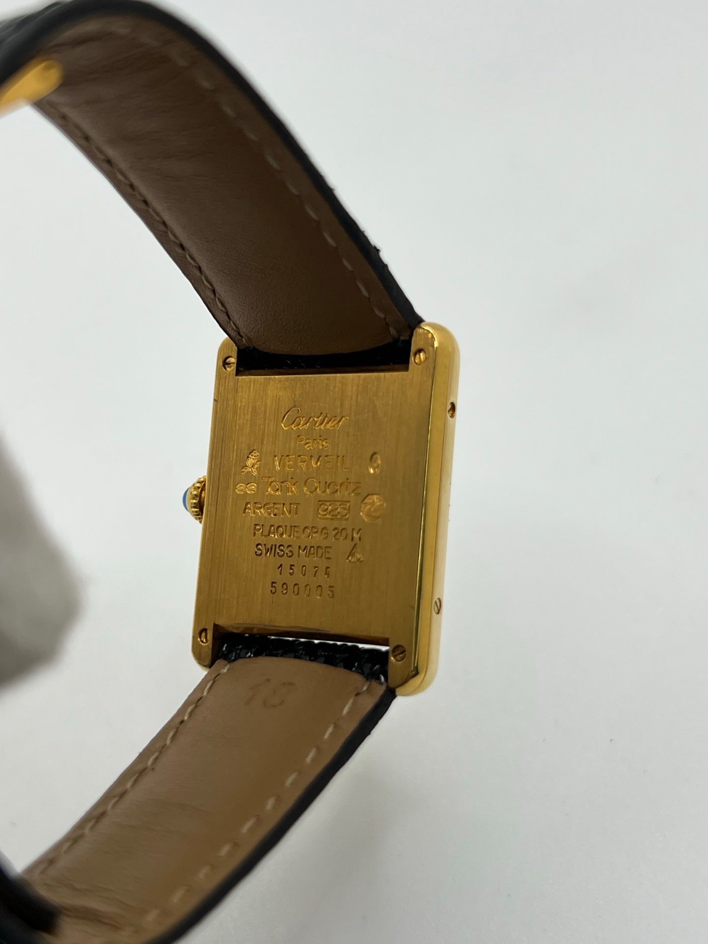 Montre Cartier Tank Vermeil référence 590005 vintage de 1989, avec boîtier rectangulaire en argent aux proportions classiques 23 x 30 mm, cadran argenté élégant avec chiffres arabes noirs et aiguilles bleuies, verre saphir et mouvement quartz. Montée sur un bracelet en cuir de lézard noir avec boucle ardillon en acier. Modèle iconique au design intemporel, livré avec son coffret et ses papiers d’origine, en très bon état.