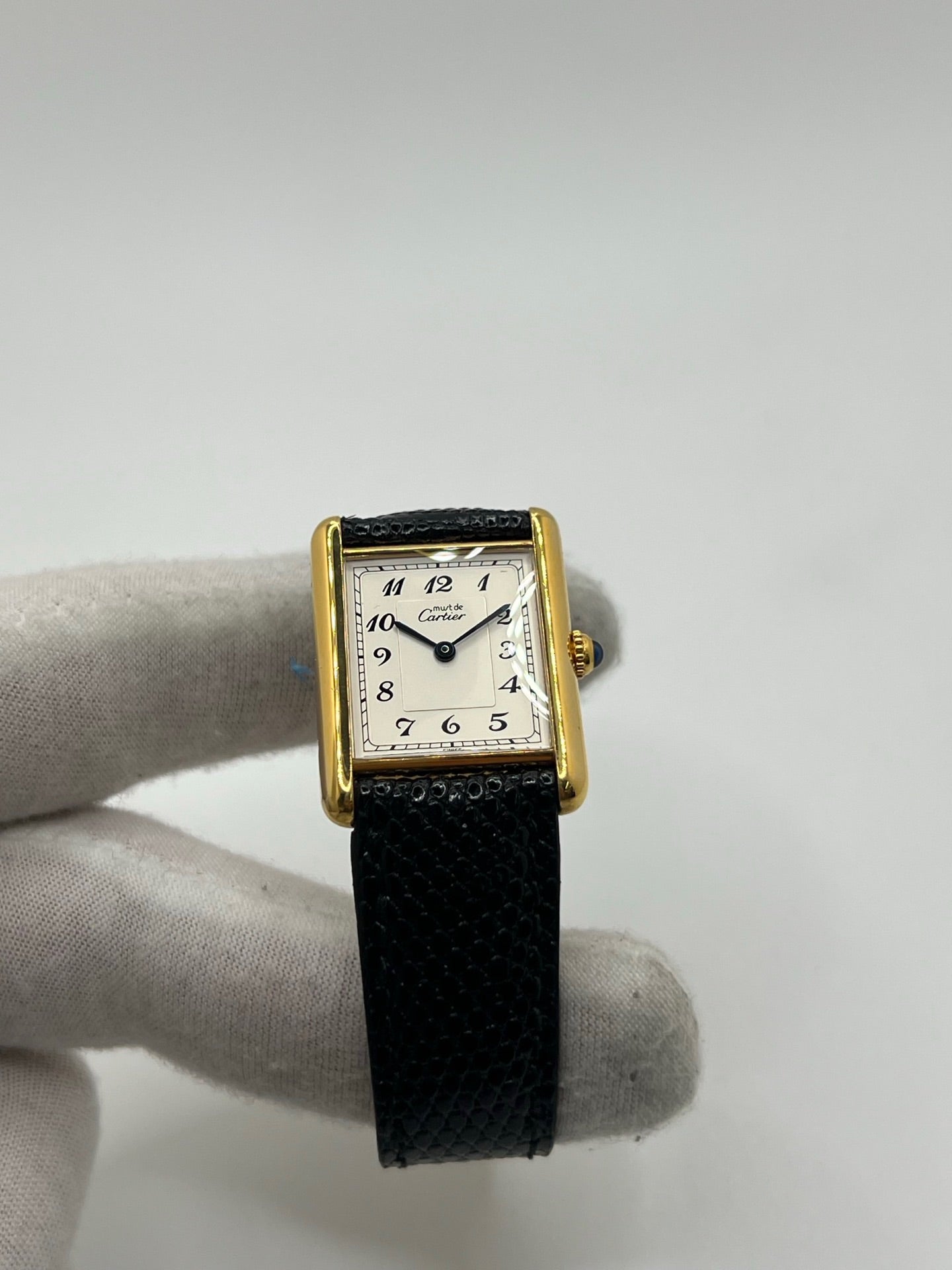 Montre Cartier Tank Vermeil référence 590005 vintage de 1989, avec boîtier rectangulaire en argent aux proportions classiques 23 x 30 mm, cadran argenté élégant avec chiffres arabes noirs et aiguilles bleuies, verre saphir et mouvement quartz. Montée sur un bracelet en cuir de lézard noir avec boucle ardillon en acier. Modèle iconique au design intemporel, livré avec son coffret et ses papiers d’origine, en très bon état.