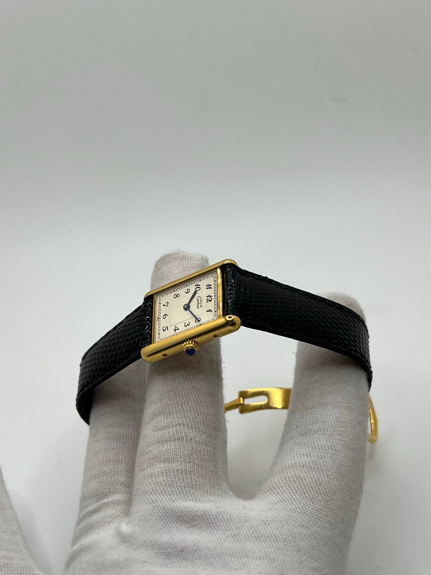 Montre Cartier Tank Vermeil référence 590005 vintage de 1989, avec boîtier rectangulaire en argent aux proportions classiques 23 x 30 mm, cadran argenté élégant avec chiffres arabes noirs et aiguilles bleuies, verre saphir et mouvement quartz. Montée sur un bracelet en cuir de lézard noir avec boucle ardillon en acier. Modèle iconique au design intemporel, livré avec son coffret et ses papiers d’origine, en très bon état.